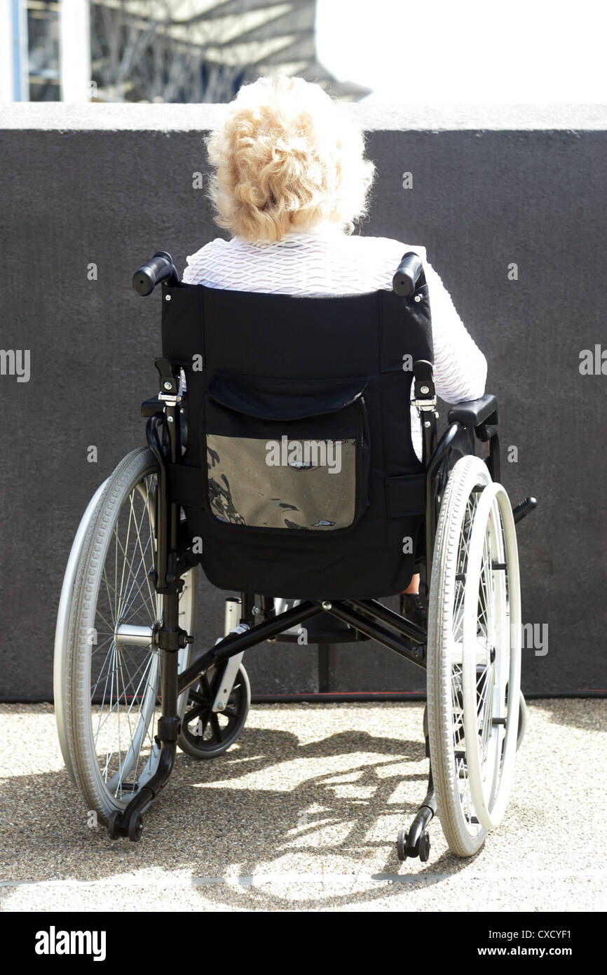 Londra, una donna su una sedia a rotelle davanti a una parete Foto Stock