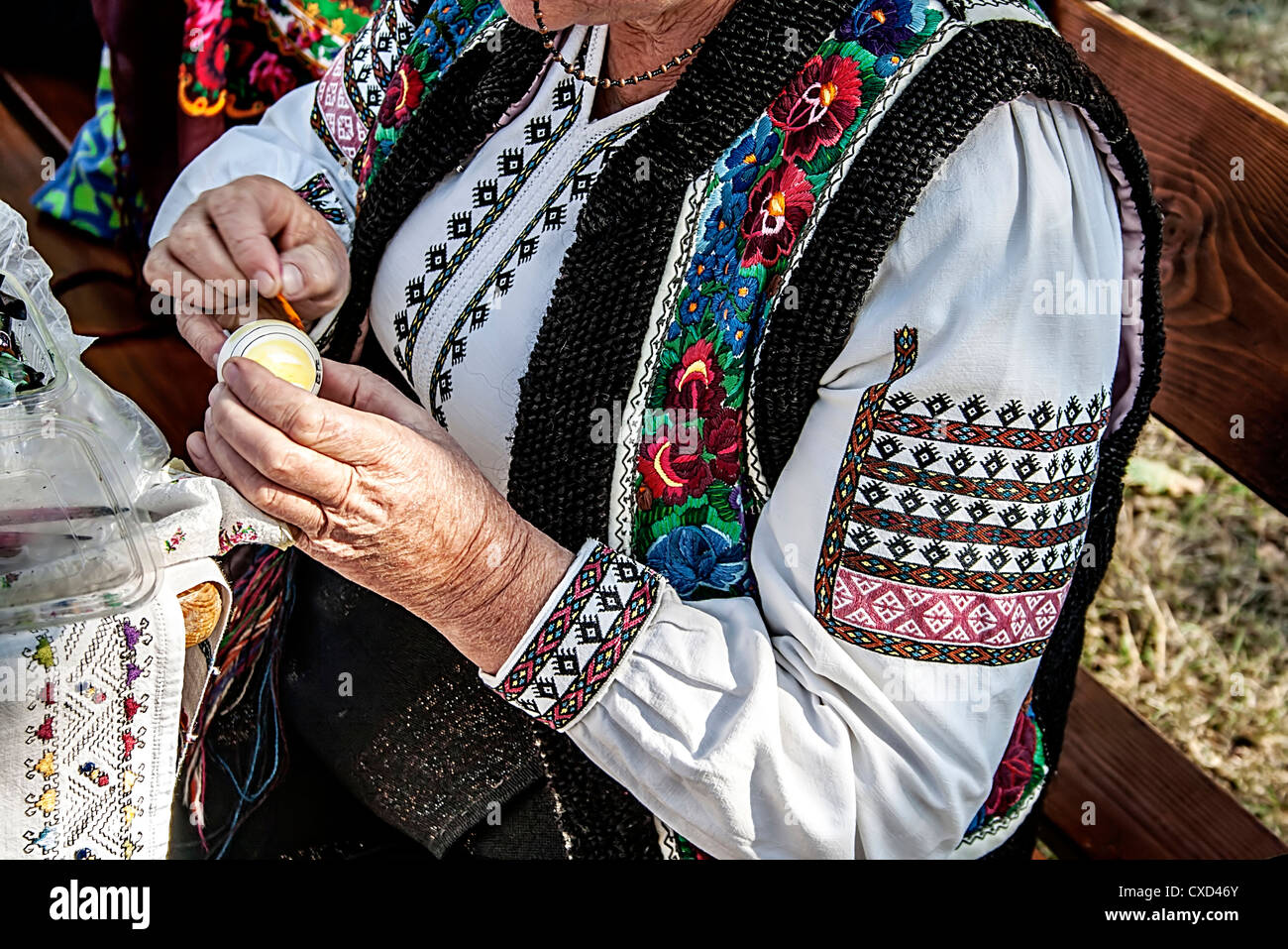 Donna rumena in costume tradizionale e pittura un uovo tradizionalmente Foto Stock