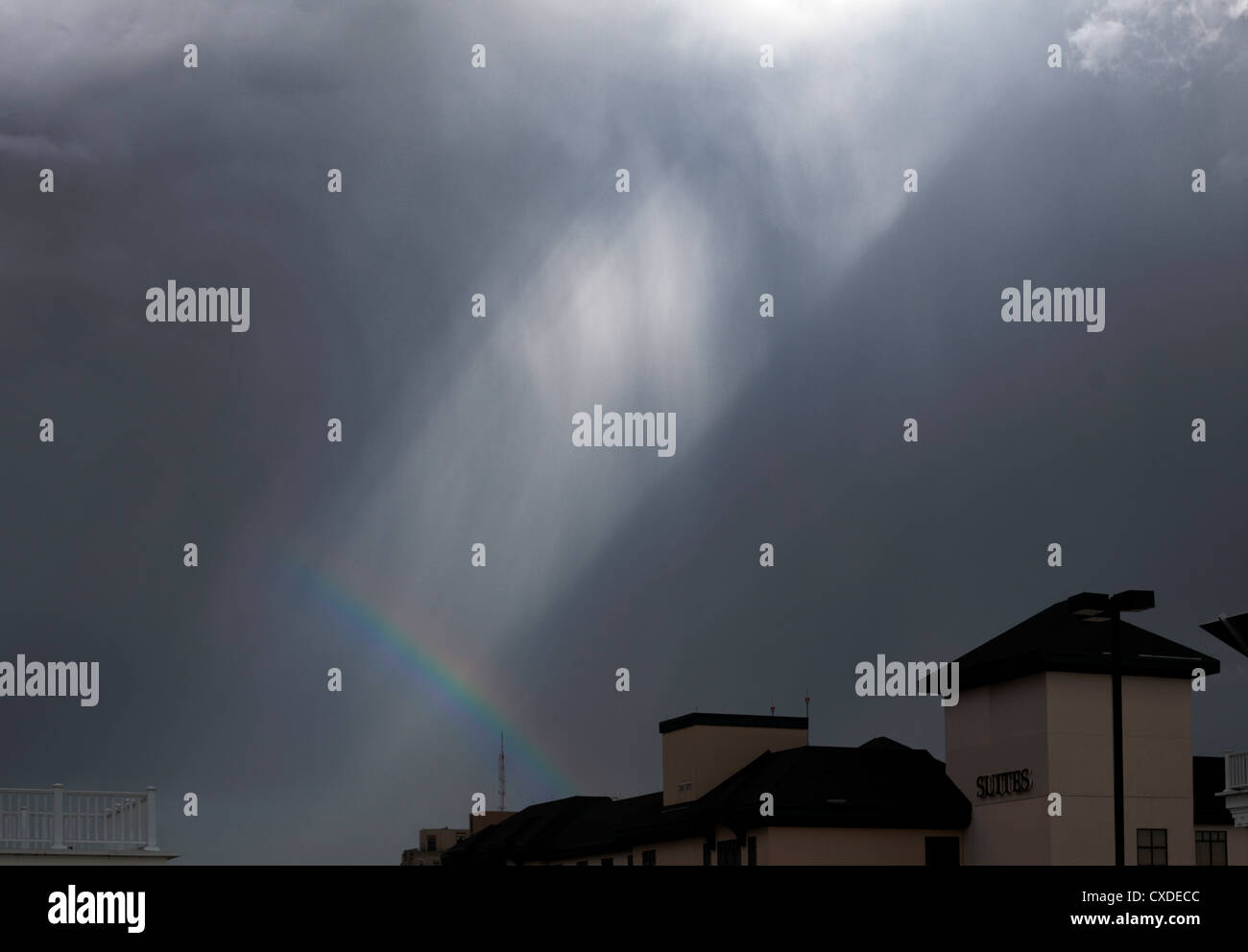 Debole rainbow al di sopra di un edificio, con raggi di luce. Rimosso il logo. Foto Stock