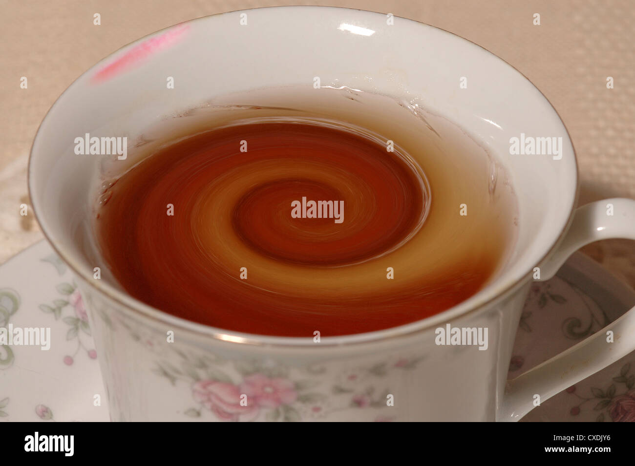 Tazza da tè riempita con tè vorticoso, con macchie di rossetto. Foto Stock