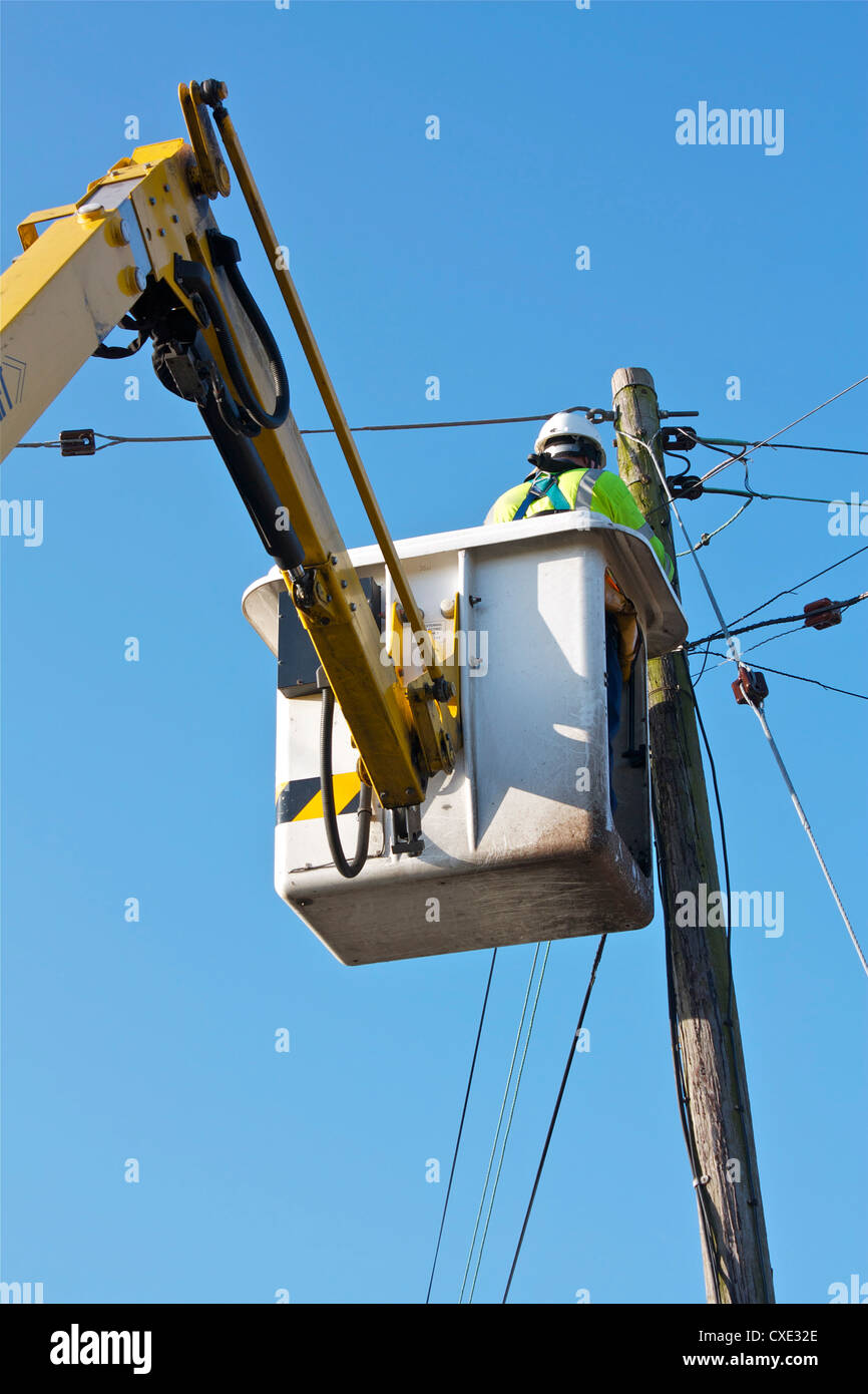 Un Telecom/Ingegnere elettrico utilizzando un Mobile elevando la piattaforma di lavoro della macchina. Foto Stock