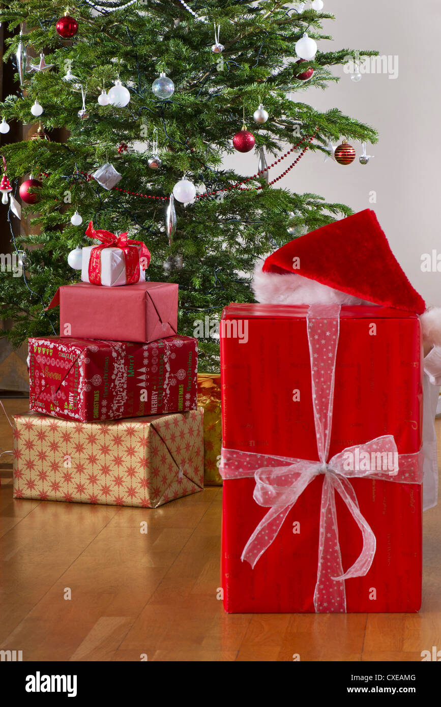 Persona in Santa hat nascondendo dietro il regalo di Natale Foto Stock