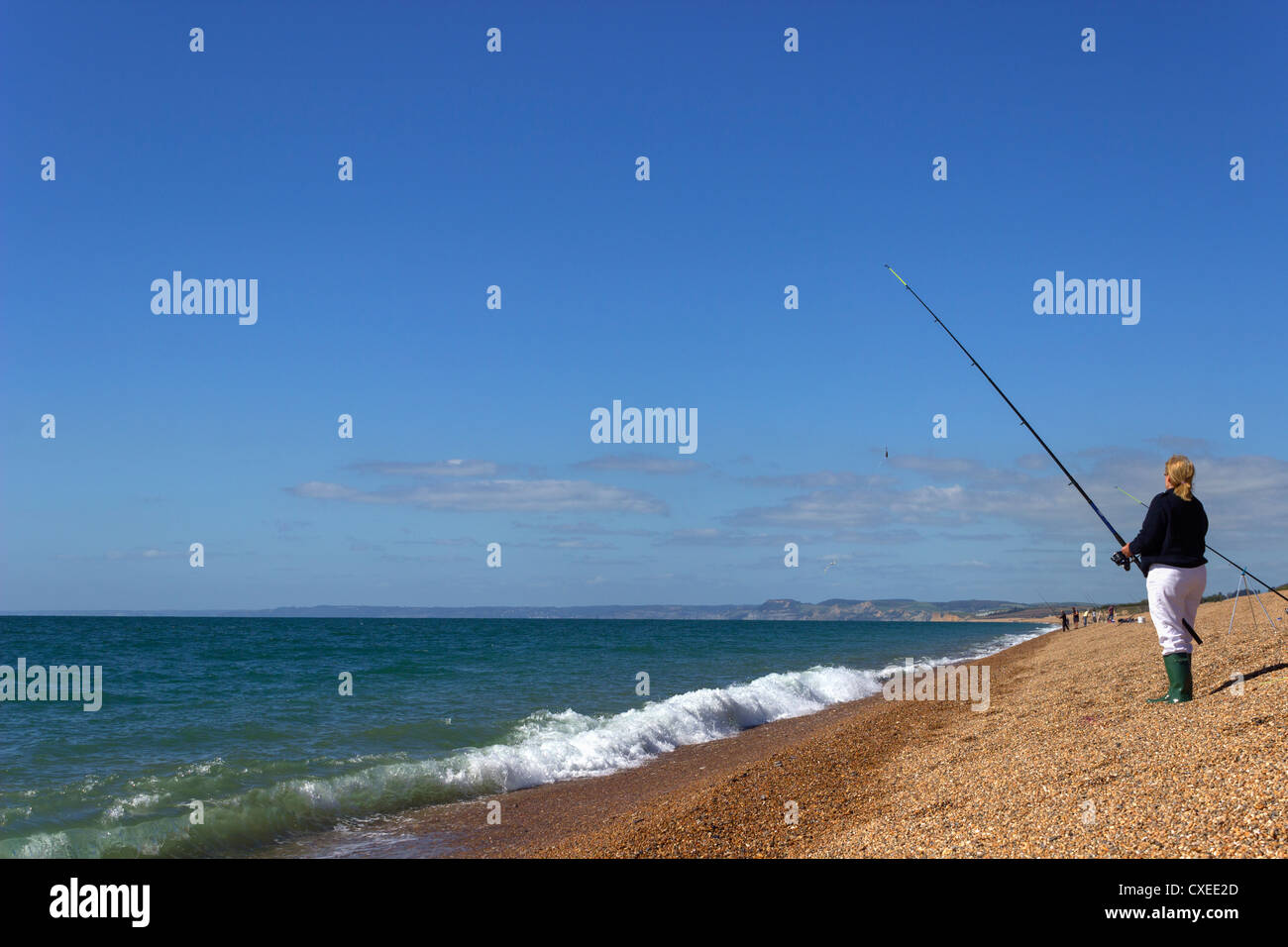 Donna della pesca in mare sulla banca Chesil Foto Stock