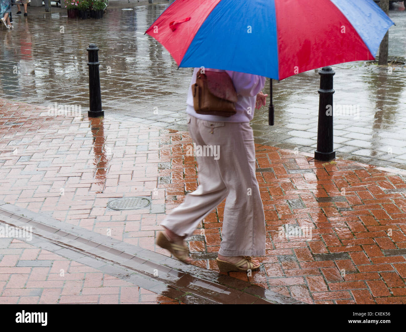 Donna camminare sotto un ombrello in caso di pioggia. Foto Stock