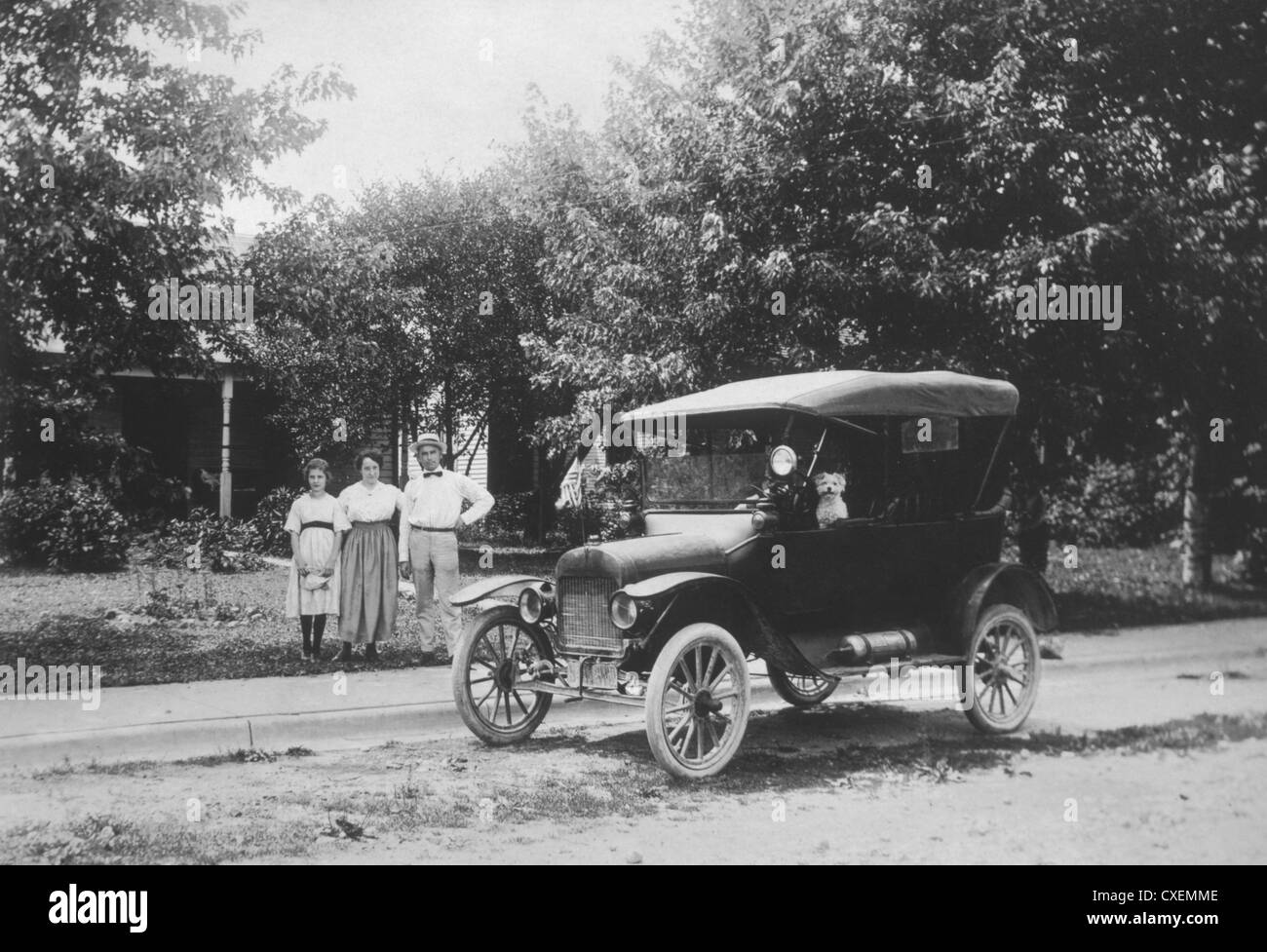 Famiglia in piedi sul marciapiede accanto al modello T Automobile, circa 1910 Foto Stock