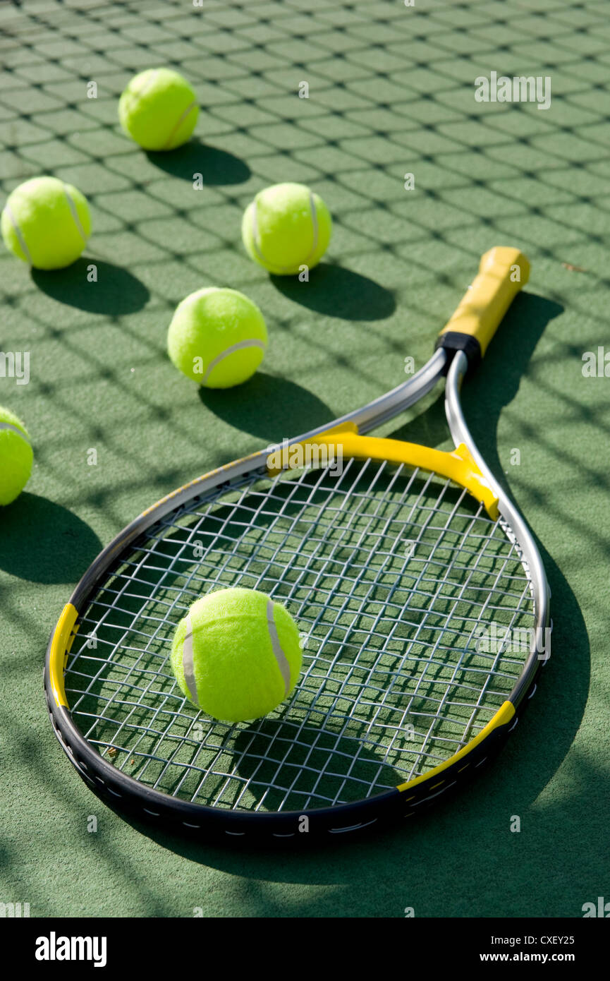 Un gruppo di palle da tennis e una racchetta da tennis su un dipinta di fresco cemento campo da tennis Foto Stock