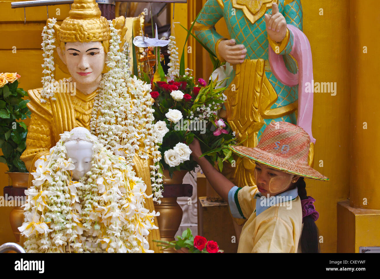 Una statua di Buddha ricoperta di fiori alla Shwedagon Paya o pagoda che risale al 1485 - YANGON, MYANAMAR Foto Stock