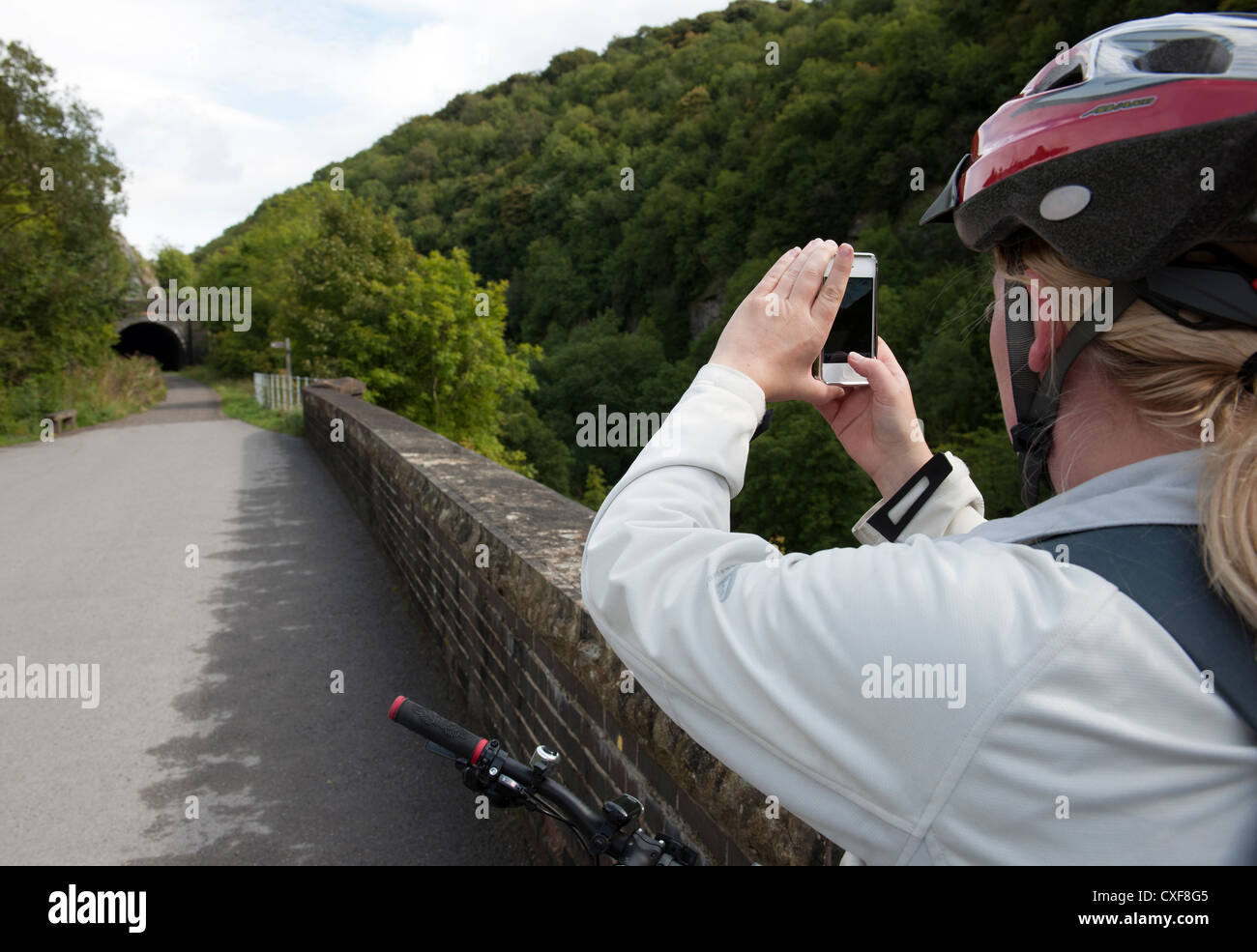 Femmina ciclista smette di fotografare con il telefono cellulare sul Monsal Trail nel Peak District, Derbyshire, Inghilterra, Regno Unito. Foto Stock