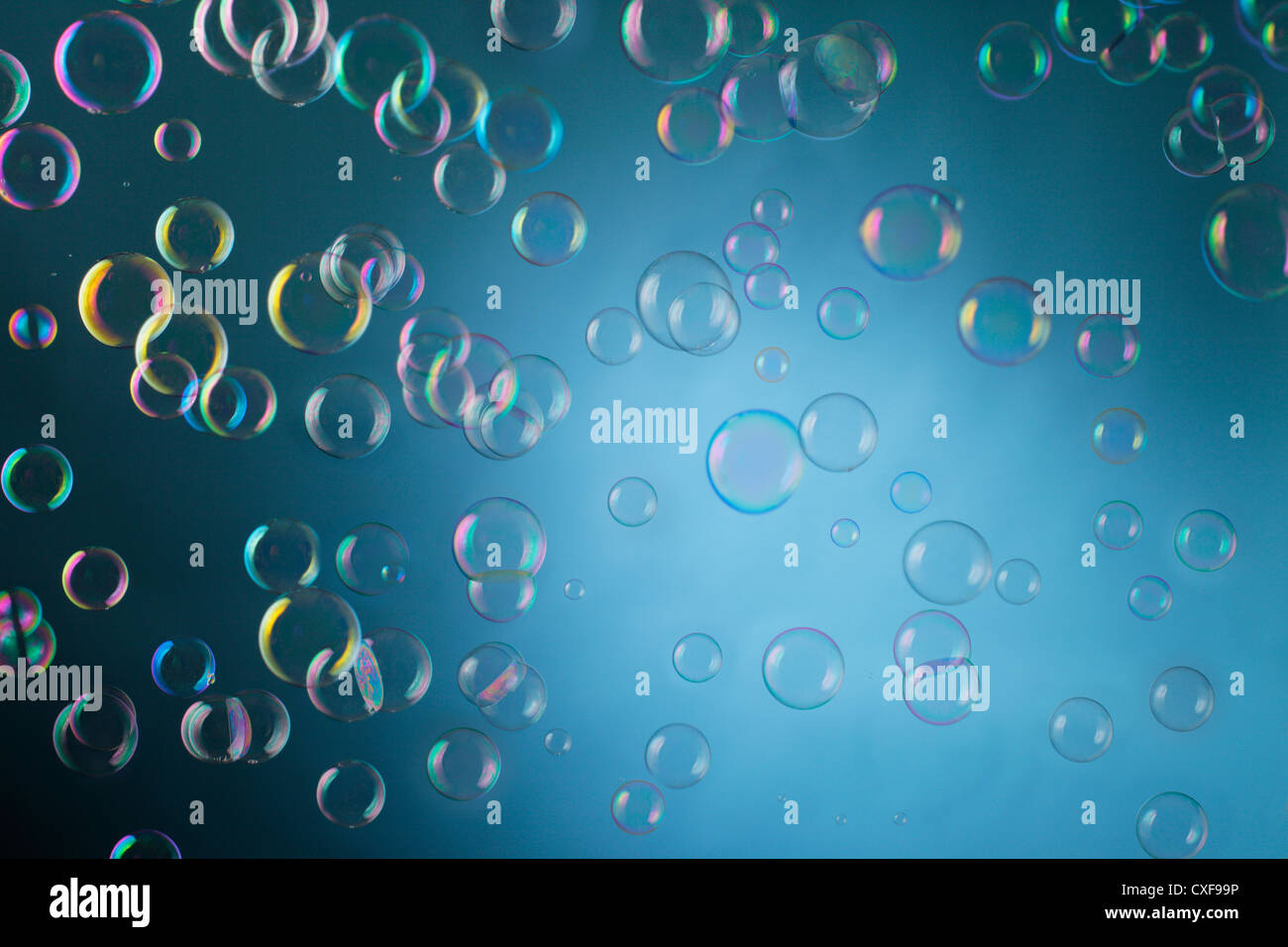 Real bolle di sapone floating mid-aria su sfondo blu. Foto Stock