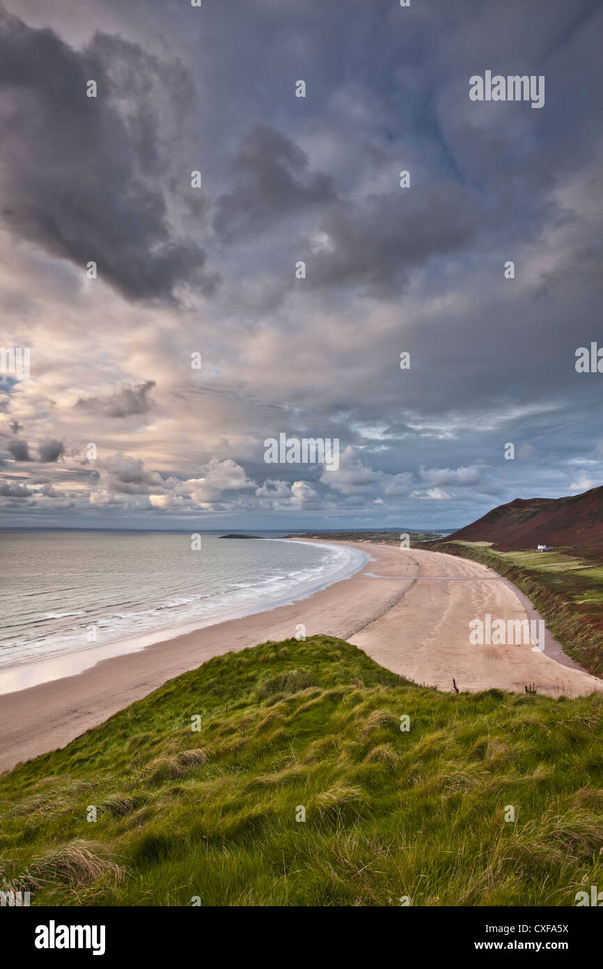 Un ultimo scoppio di luce oltre le sabbie della Baia di Rhossili sulla Penisola di Gower in Galles. Foto Stock