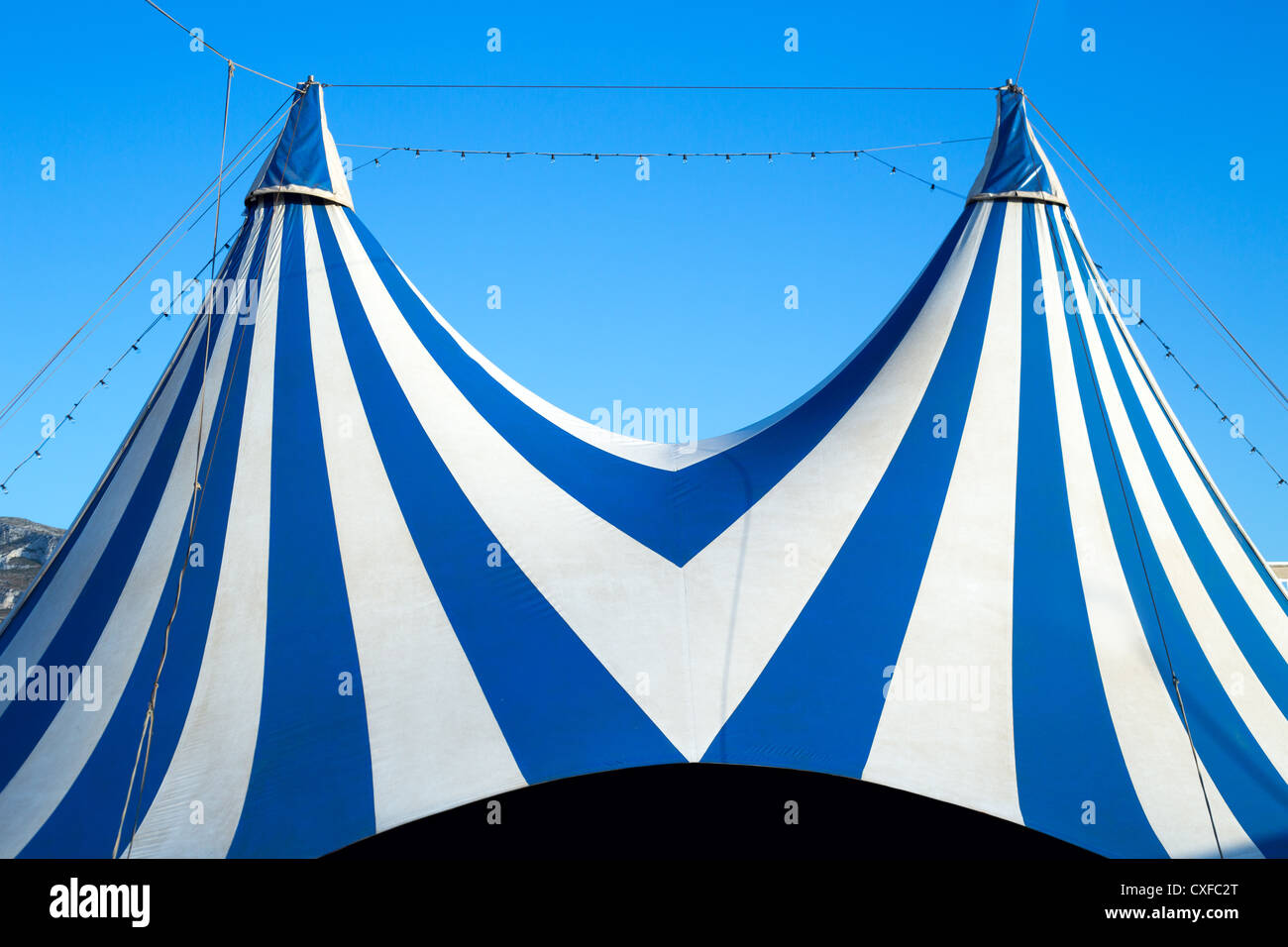 Tenda del circo spogliato di colore blu e bianco nel cielo chiaro Foto Stock