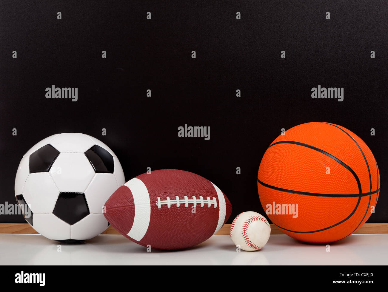 Assortiti palle sportive di fronte a una lavagna nera con spazio di copia Foto Stock