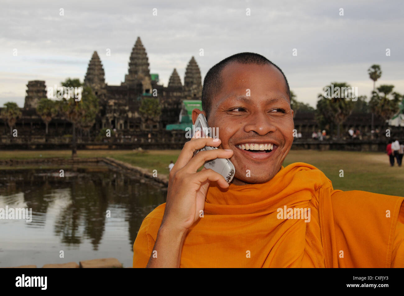 Il vecchio incontra il nuovo. Monaco che parla nel suo telefono cellulare nella parte anteriore del principale tempio di Angkor Foto Stock