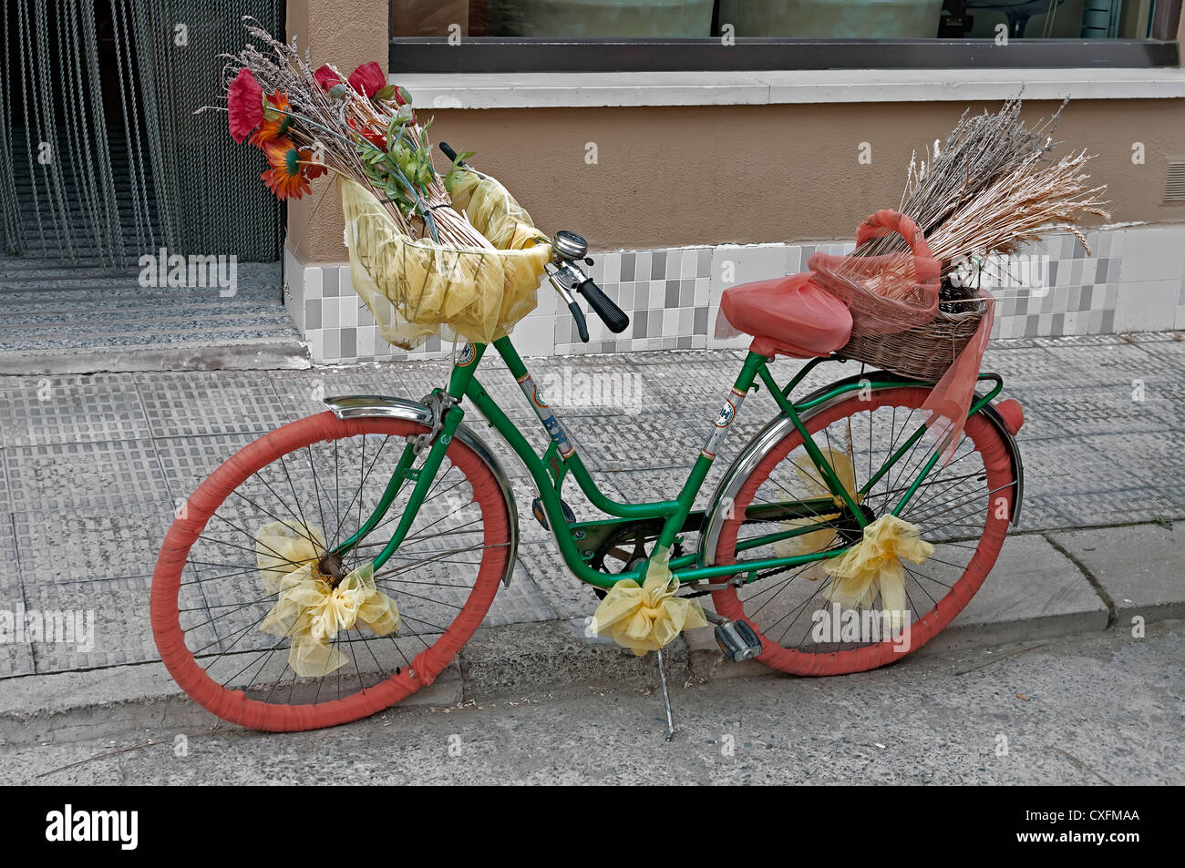 Donna bike stop sul marciapiede della mostra street e fregio decorato con fiori Foto Stock