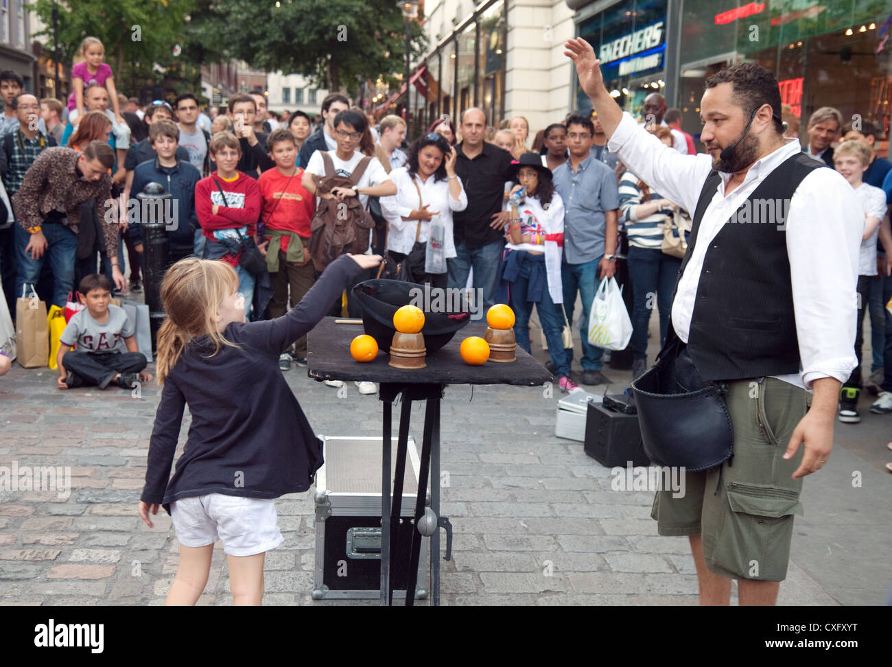 Un bambino dare soldi a un esecutore street, Covent Garden, Londra UK Foto Stock