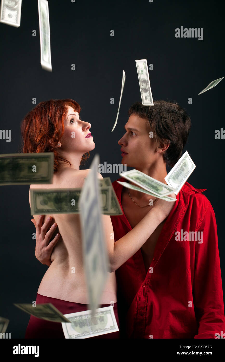 Giovane uomo e donna sotto il denaro cadono Foto Stock