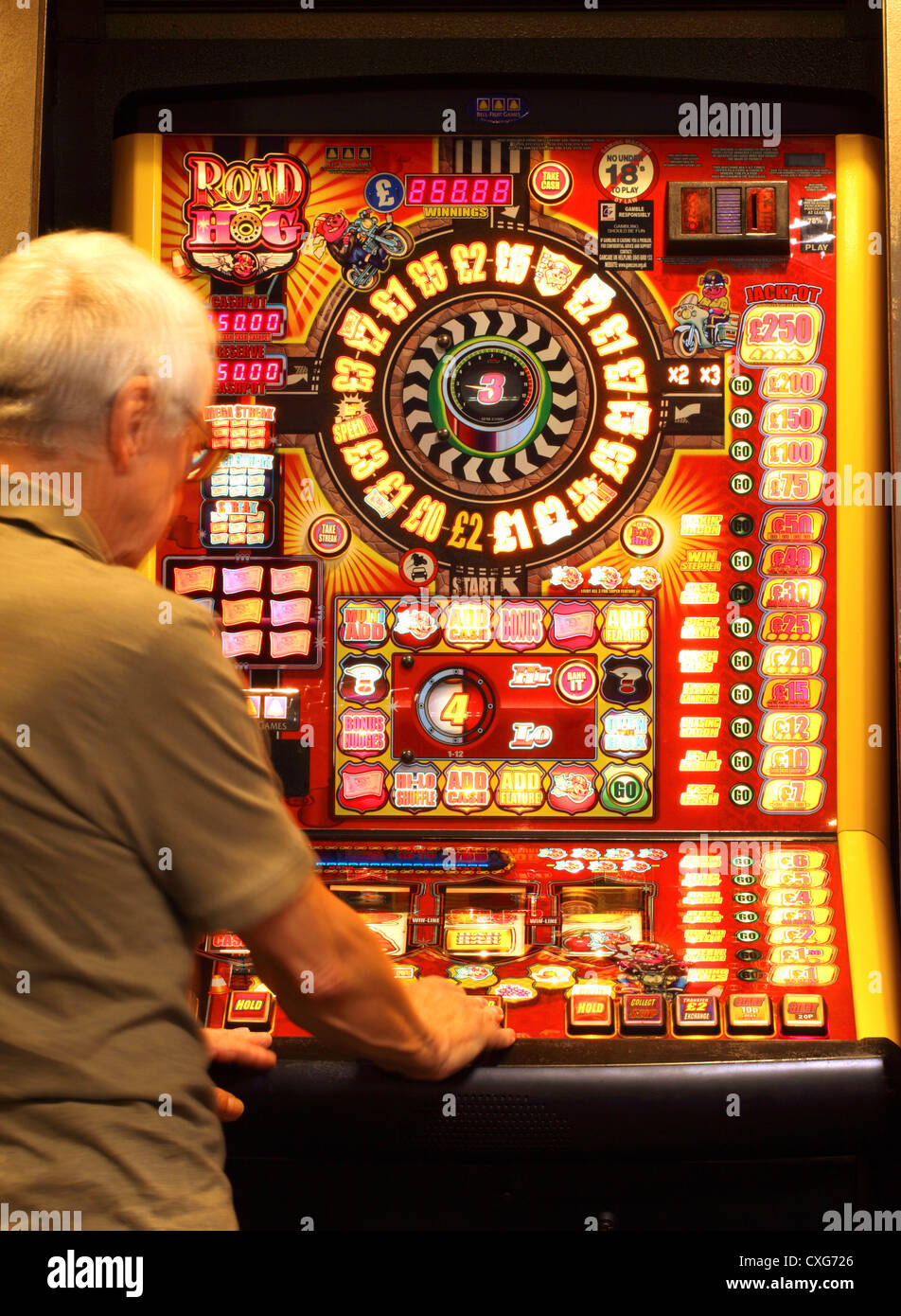 Un uomo di circa 60 anni , (mostra un leggero movimento) giocando su una slot machine Foto Stock