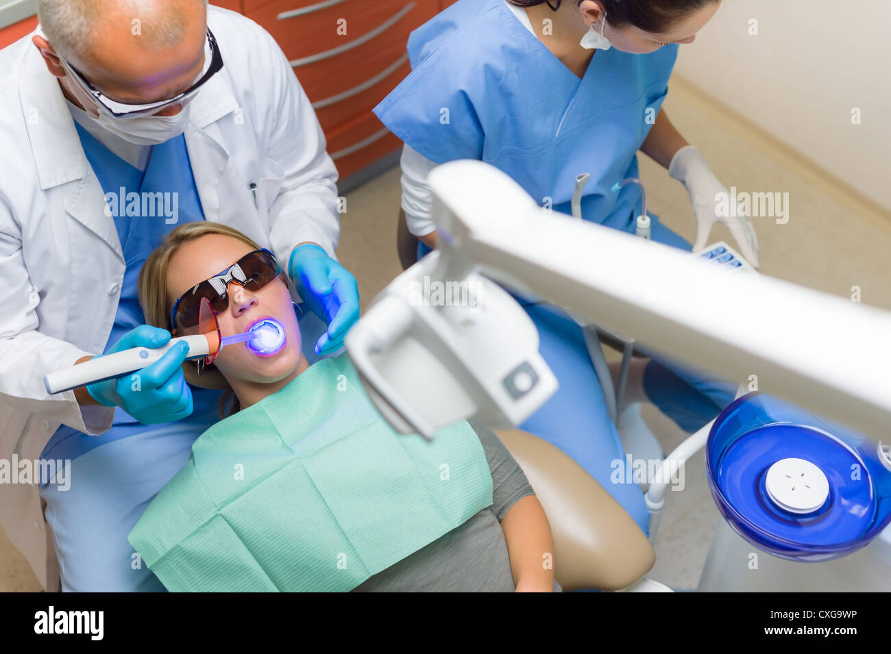 Giovane donna paziente hanno un intervento di chirurgia dentale dentista utilizzare la lampada UV Foto Stock