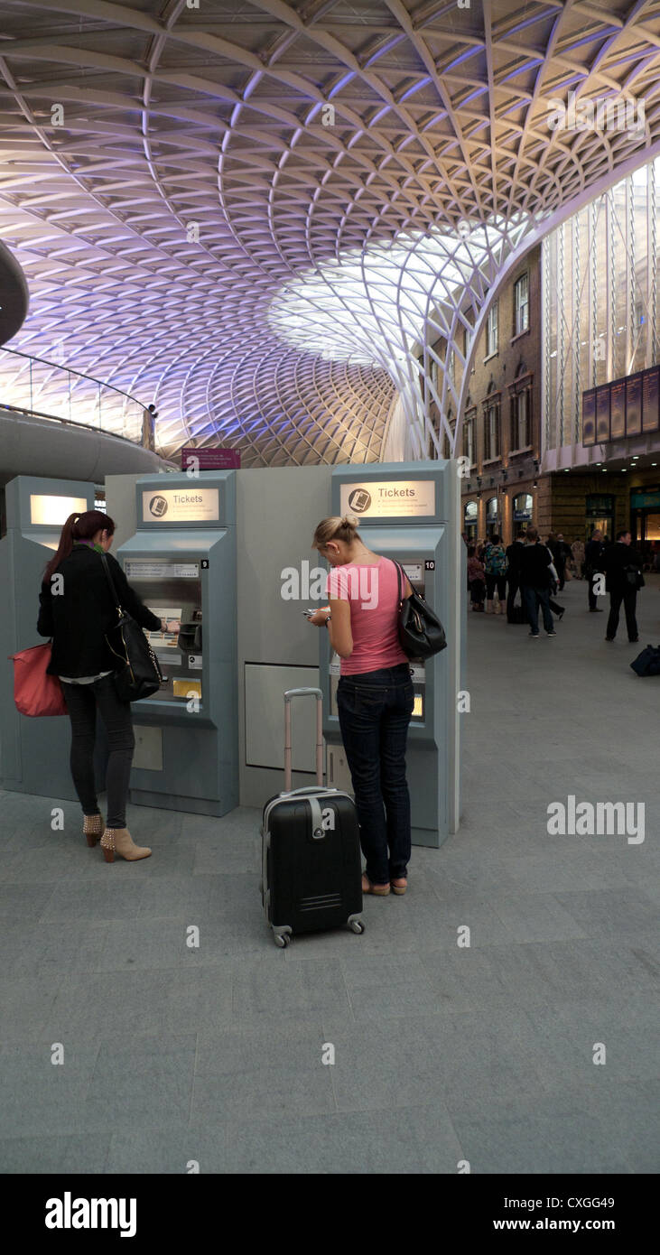 Persone che acquistano i biglietti del treno all'interno di King Cross Stazione ferroviaria concourse ticket Hall Londra Inghilterra REGNO UNITO Foto Stock