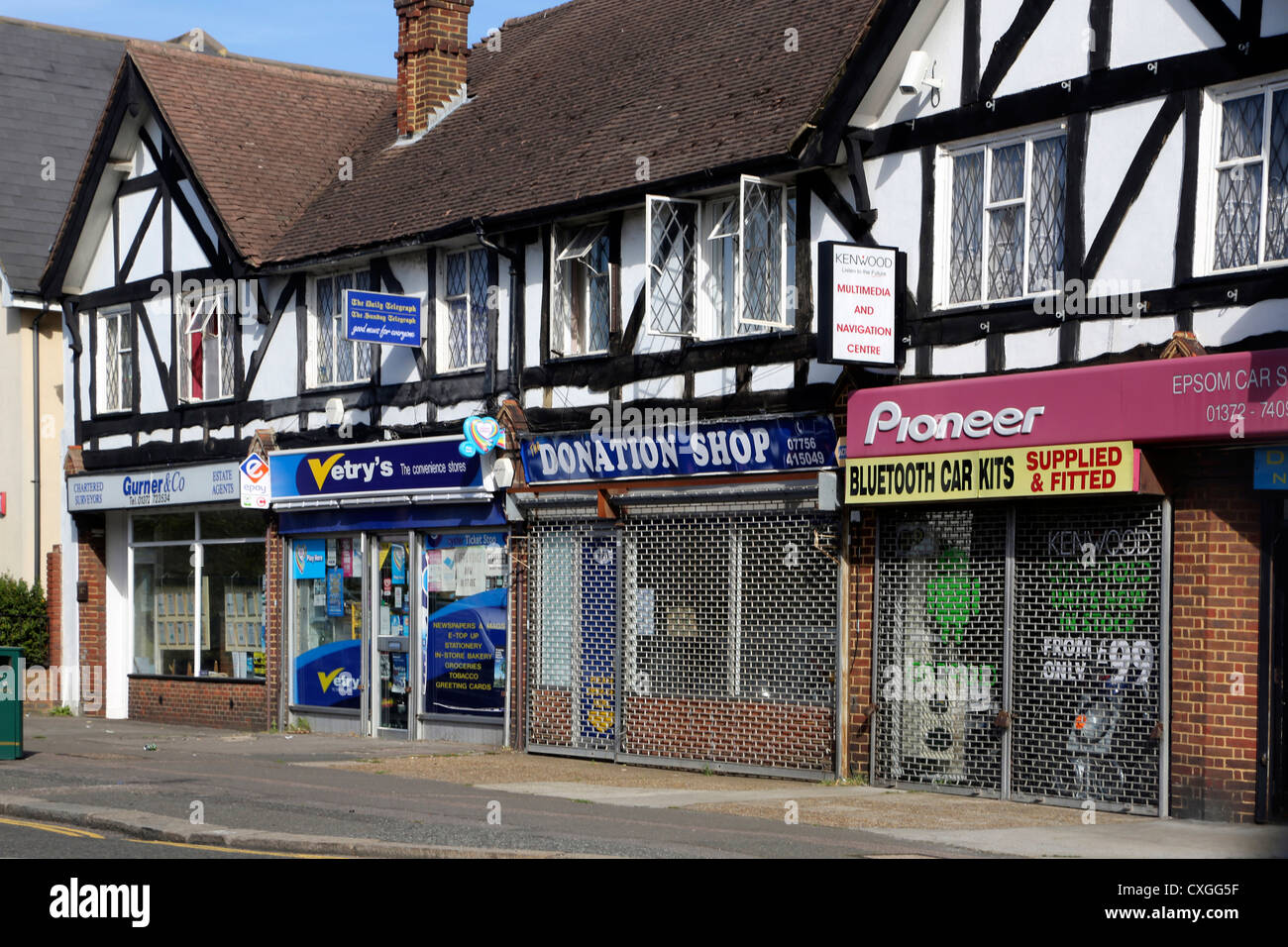Epsom Surrey in Inghilterra sfilata di Negozi Negozio di donazione e di Pioneer Accessori Auto Shop con persiane in basso Foto Stock