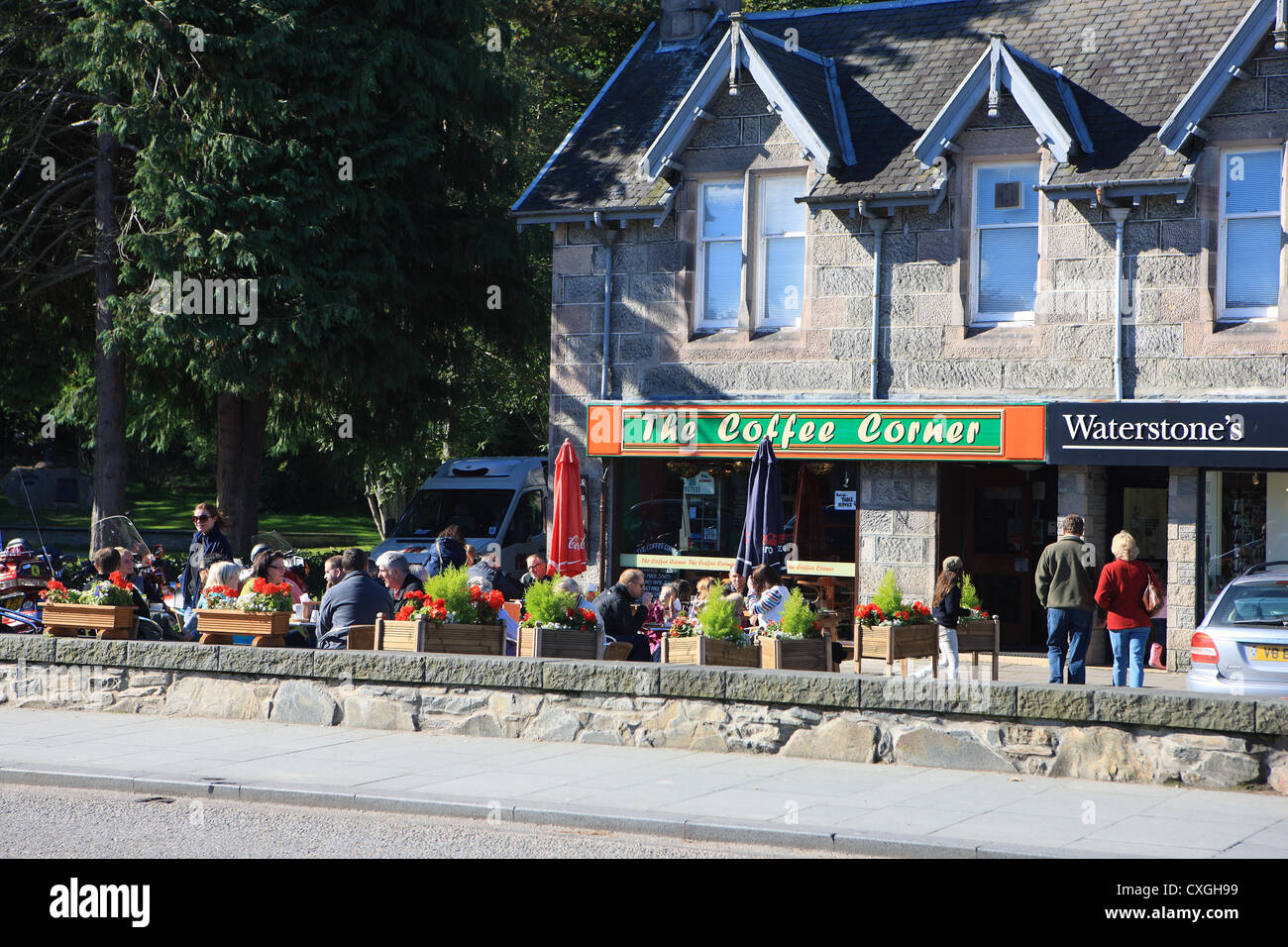 Aviemore - persone sedute in autunno il sole al di fuori di un cafe in Aviemore nelle Highlands scozzesi Foto Stock