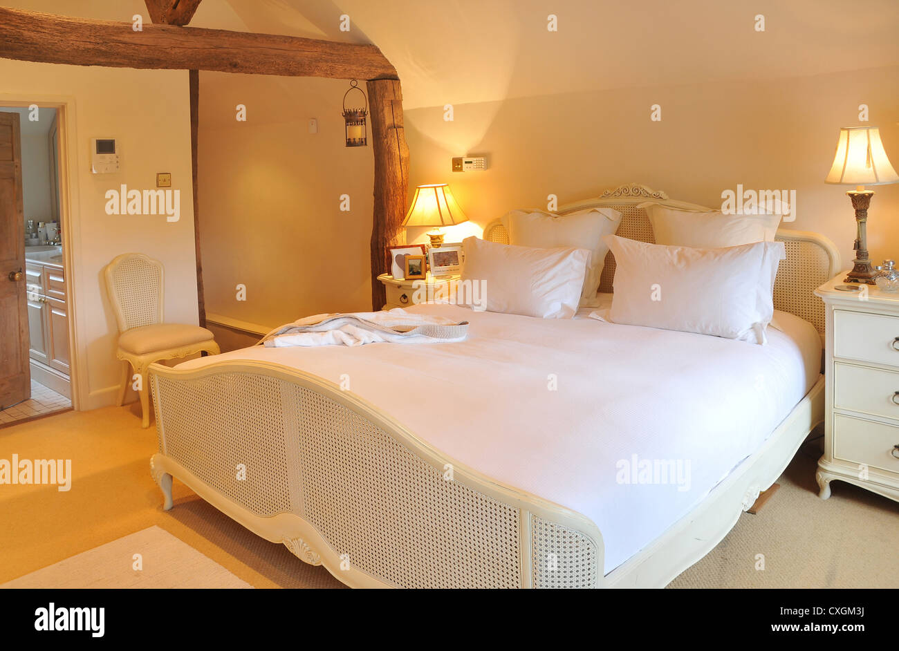 L'interno progettato da letto di un cottage inglese con letto matrimoniale, comodini, luci, sedie e bagno en suite. Foto Stock