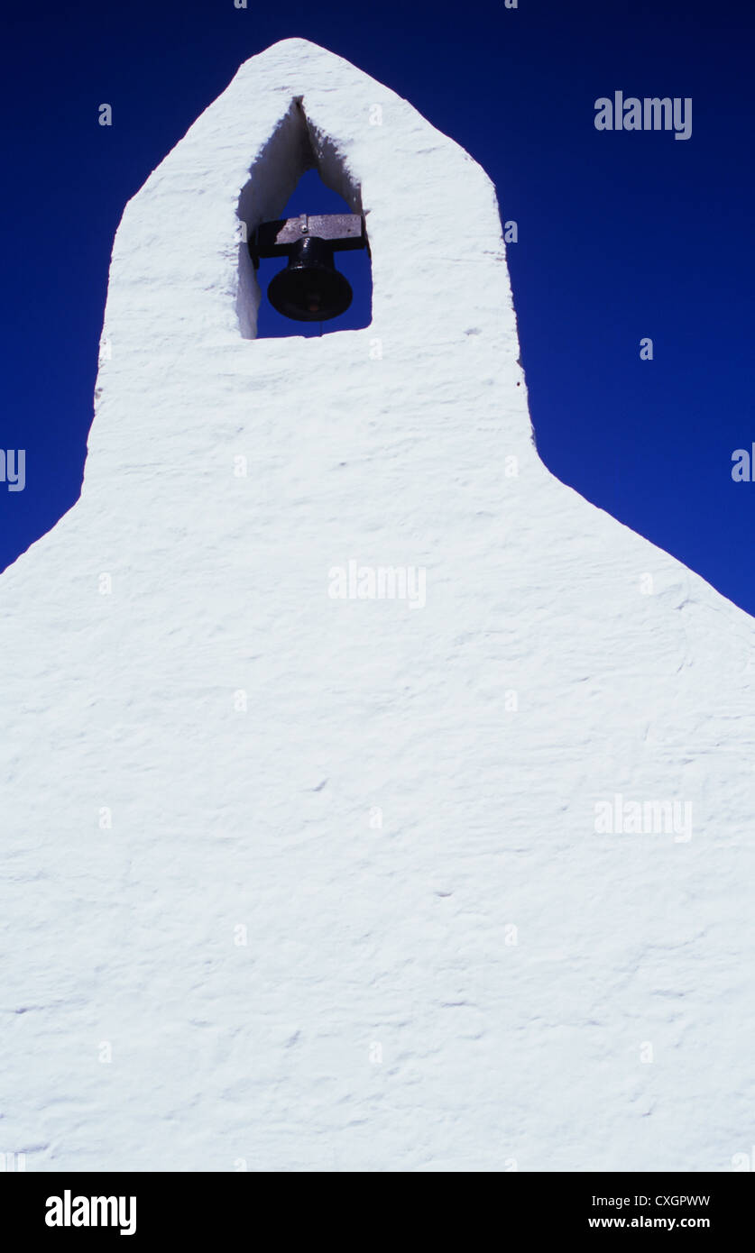 Dettaglio di fine muro di pietra della chiesa o cappella dipinta di bianco con apertura per Campana sotto il profondo blu del cielo Foto Stock