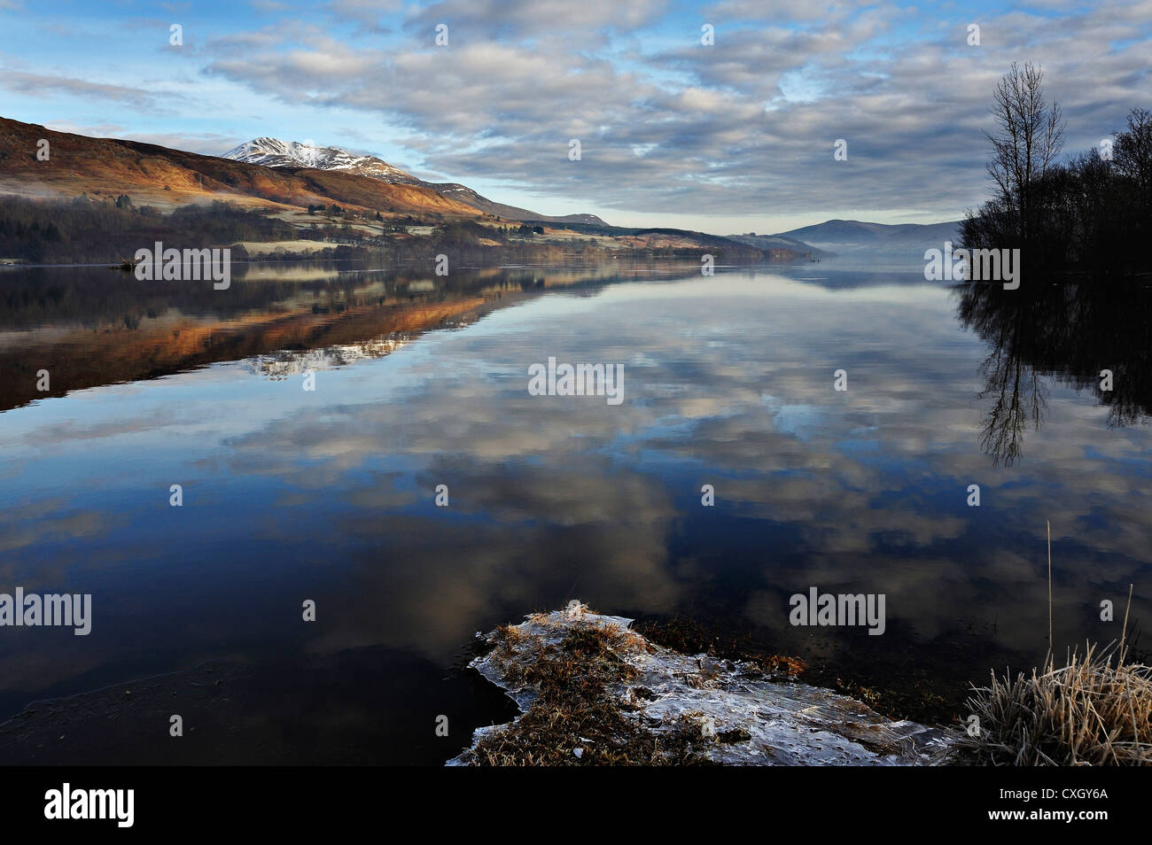 Icy sponde del Loch Tay con distante snow-capped Beinn Ghlas nella gamma Lawers, Killin, Scozia Foto Stock