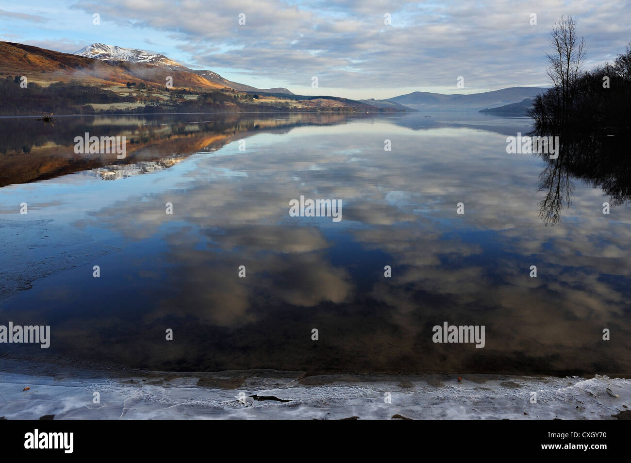 Icy sponde del Loch Tay con distante snow-capped Beinn Ghlas nella gamma Lawers, Killin, Scozia Foto Stock