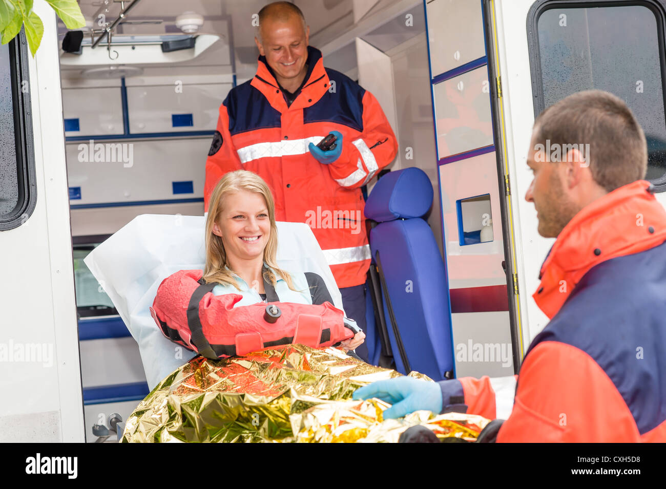 Donna con braccio rotto in ambulanza paramedici incidente aiutando vittima Foto Stock