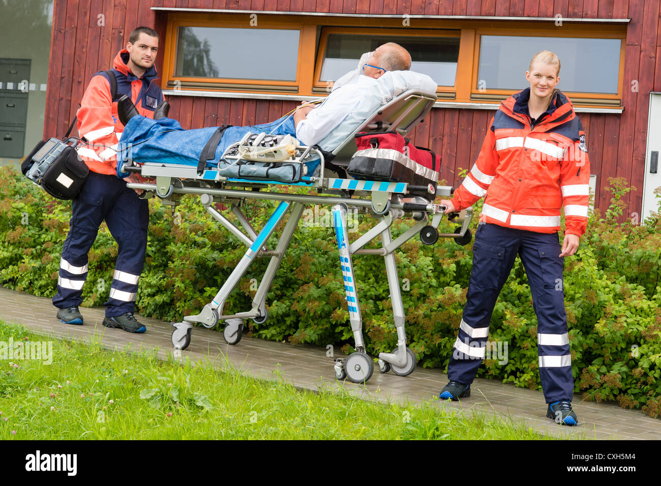 I paramedici con paziente sul lettino di emergenza aiuti ambulanza donna uomo Foto Stock
