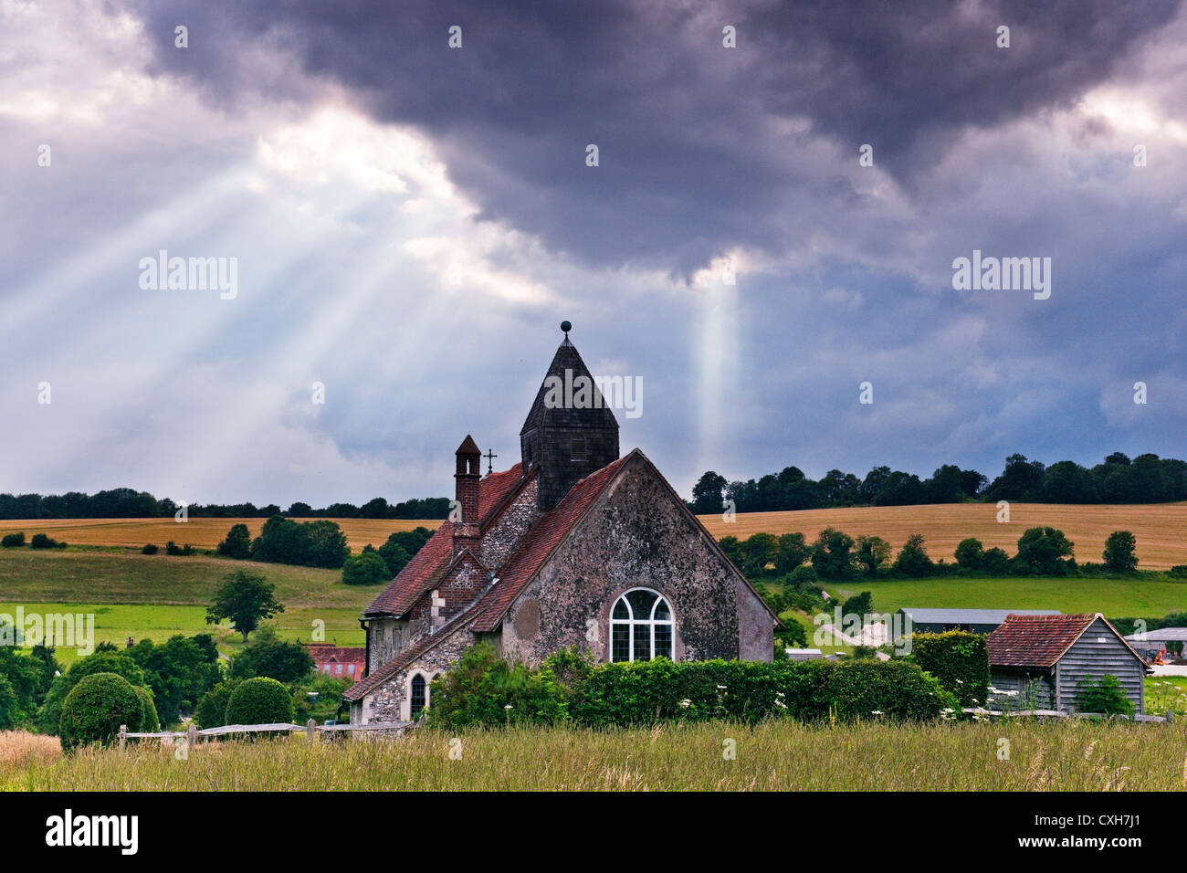 St Huberts chiesa in Idsworth Hampshire cercando da est con i raggi del sole proveniente attraverso le nuvole Foto Stock