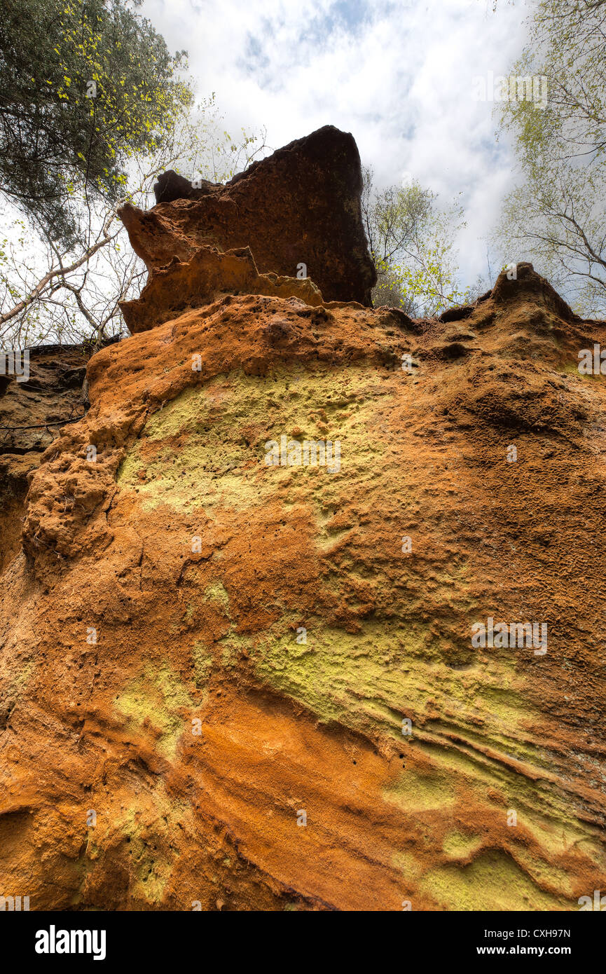 Greensand Ridge depositi di arenaria come diversi strati e ricchi colori arancione ai piedi di una ripida rupe isolata di fronte Foto Stock