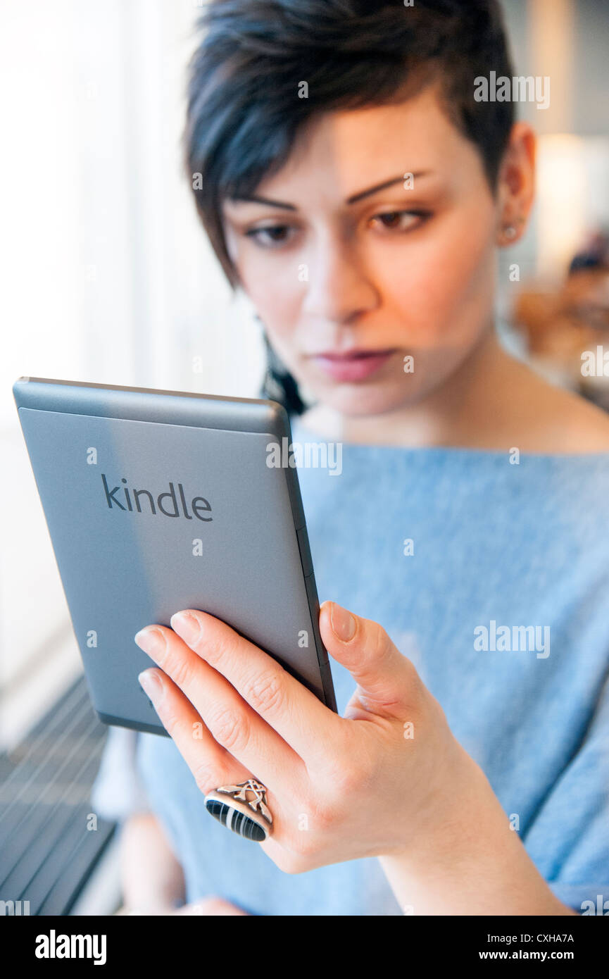 Giovane donna la lettura di ebook su un Amazon Kindle, England, Regno Unito Foto Stock
