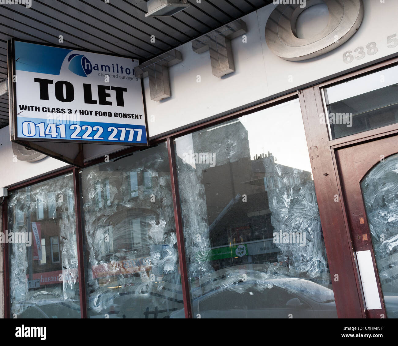 Negozio chiuso con finestre bianche e con unità al dettaglio per lasciare l'accesso a Clarkston, Glasgow. Foto Stock