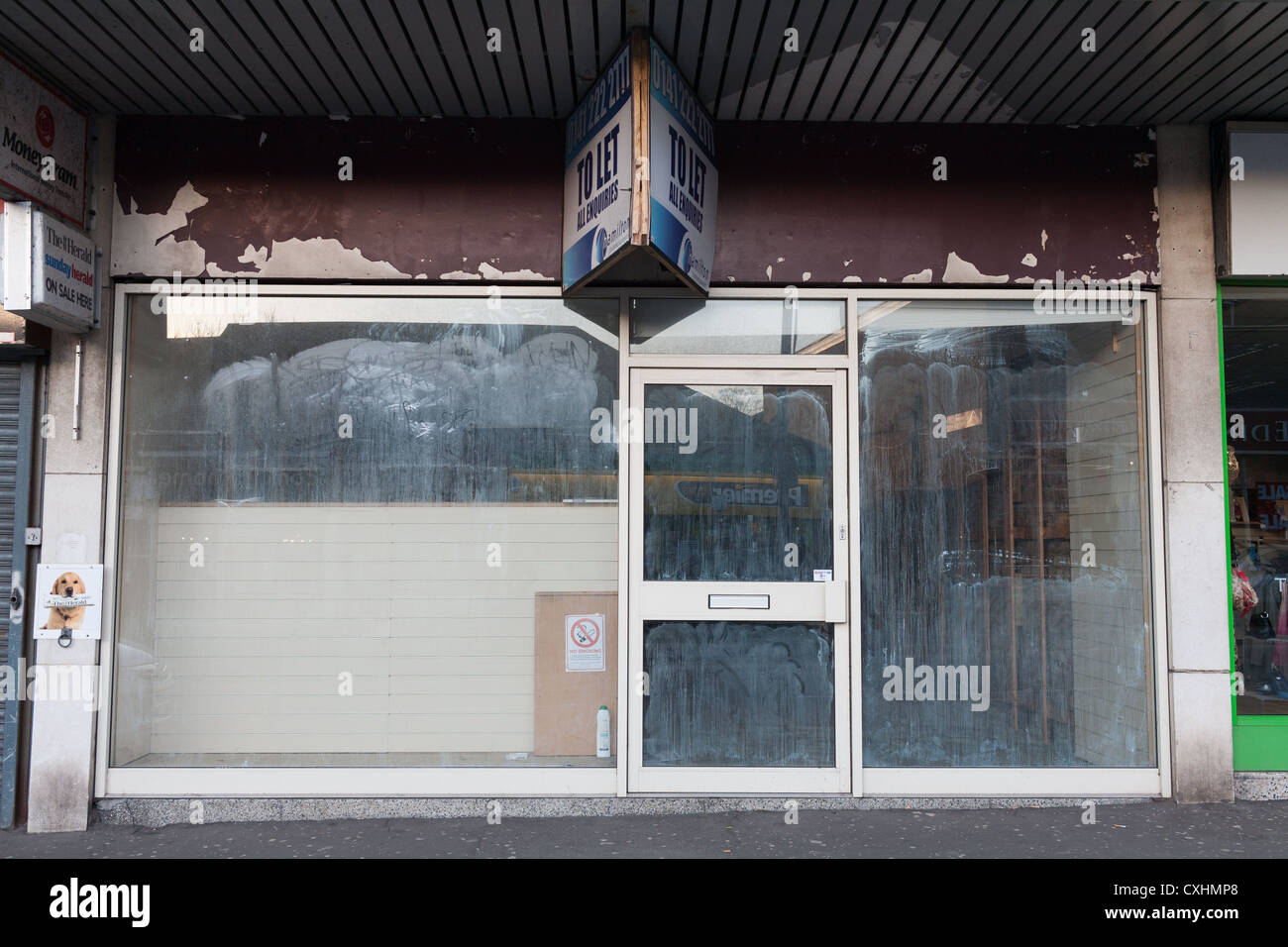 Negozio chiuso con finestre bianche e con unità al dettaglio per lasciare l'accesso a Clarkston, Glasgow. Foto Stock