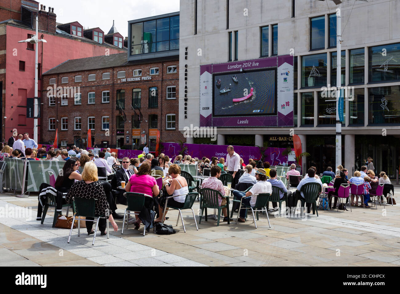 Guardare la gente una BBC avanzamento delle Olimpiadi di Londra 2012 su un grande schermo in Millenium Square, Leeds. Foto Stock