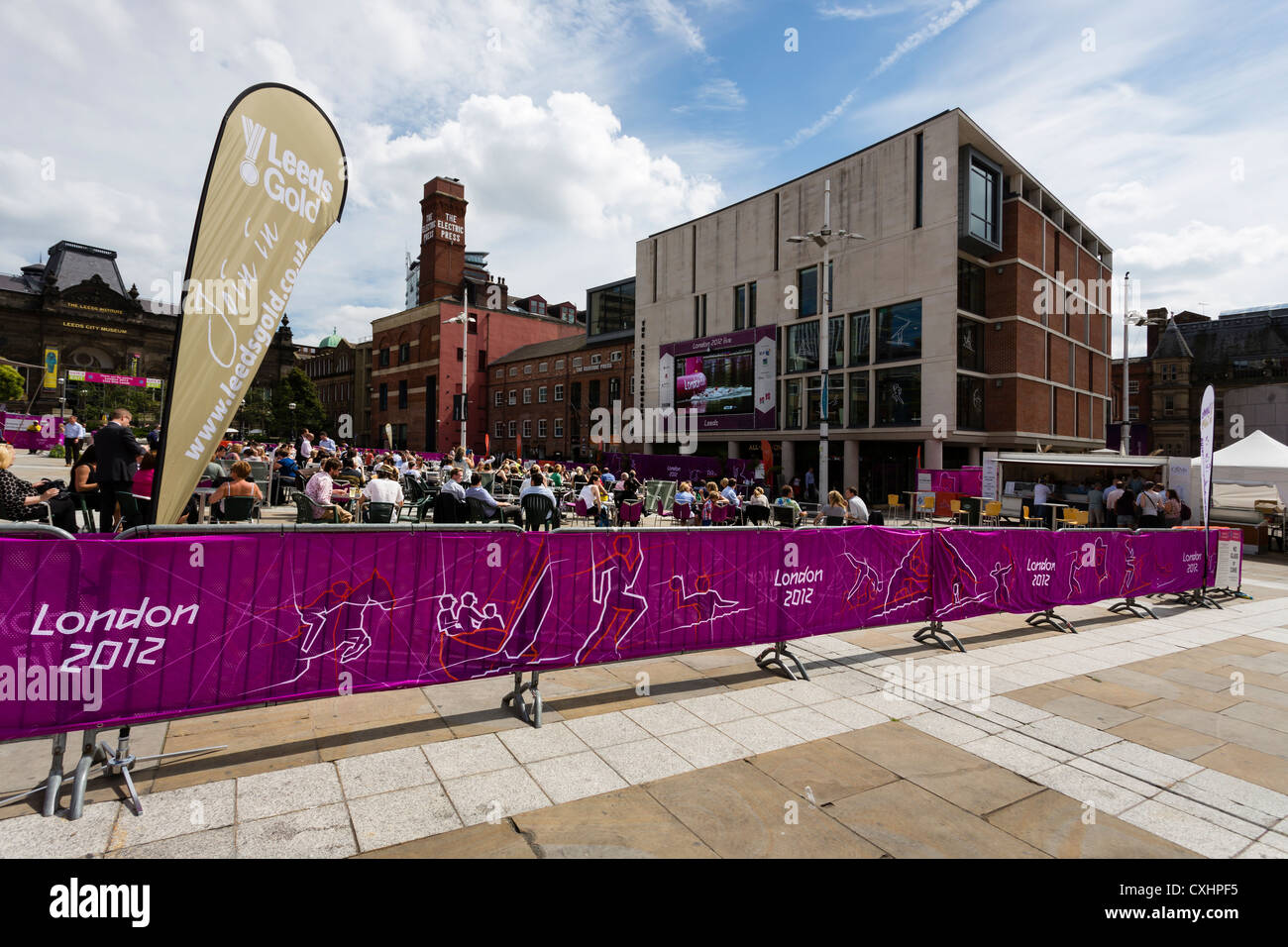 Guardare la gente una BBC avanzamento delle Olimpiadi di Londra 2012 su un grande schermo in Millenium Square, Leeds. Foto Stock