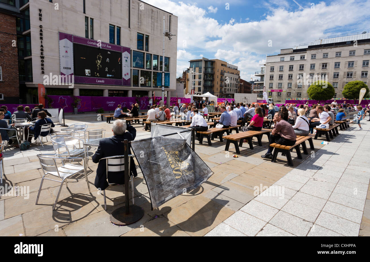 Guardare la gente una BBC avanzamento delle Olimpiadi di Londra 2012 su un grande schermo in Millenium Square, Leeds. Foto Stock
