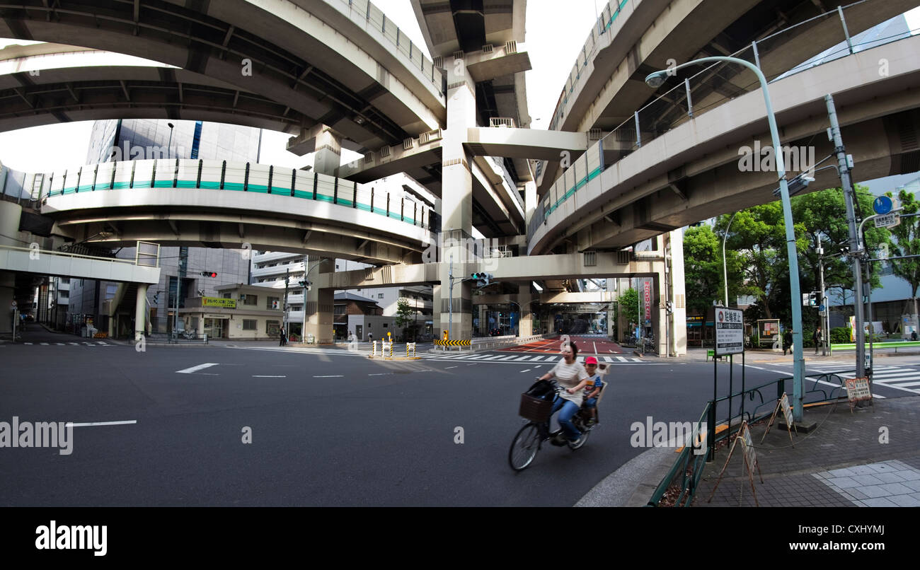 Ciclista pedalando attraverso vuoto interscambio stradale, Tokyo, Giappone Foto Stock