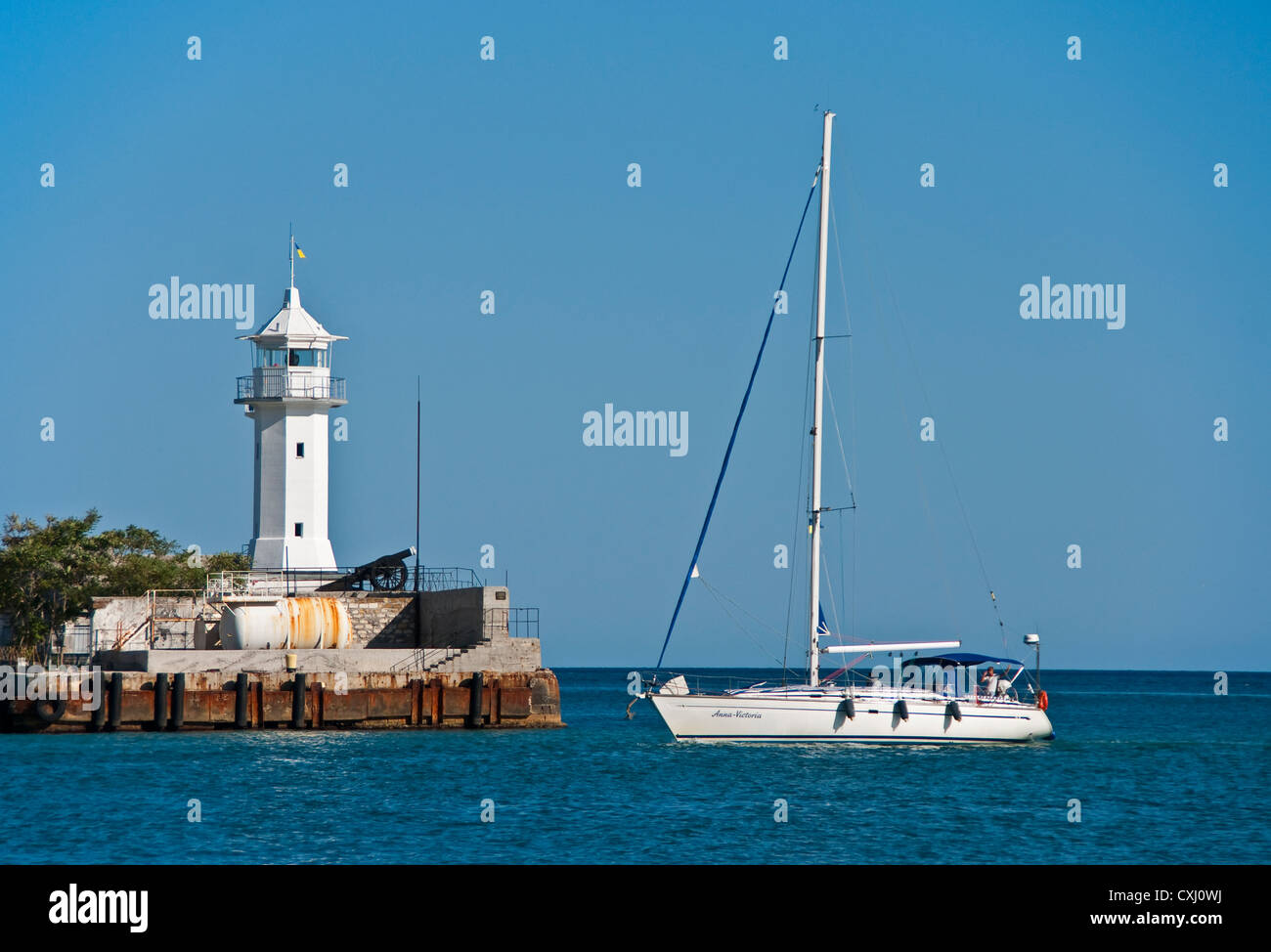Barca a vela passando faro nel porto di Yalta Foto Stock