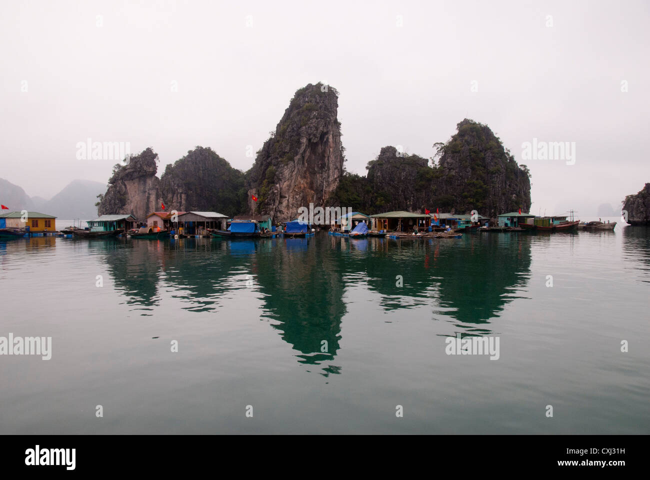 Villaggio galleggiante calcaree e carsiche formazioni rocciose, Halong Bay, Vietnam Foto Stock