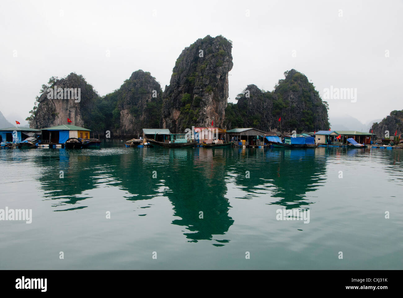 Villaggio galleggiante calcaree e carsiche formazioni rocciose, Halong Bay, Vietnam Foto Stock