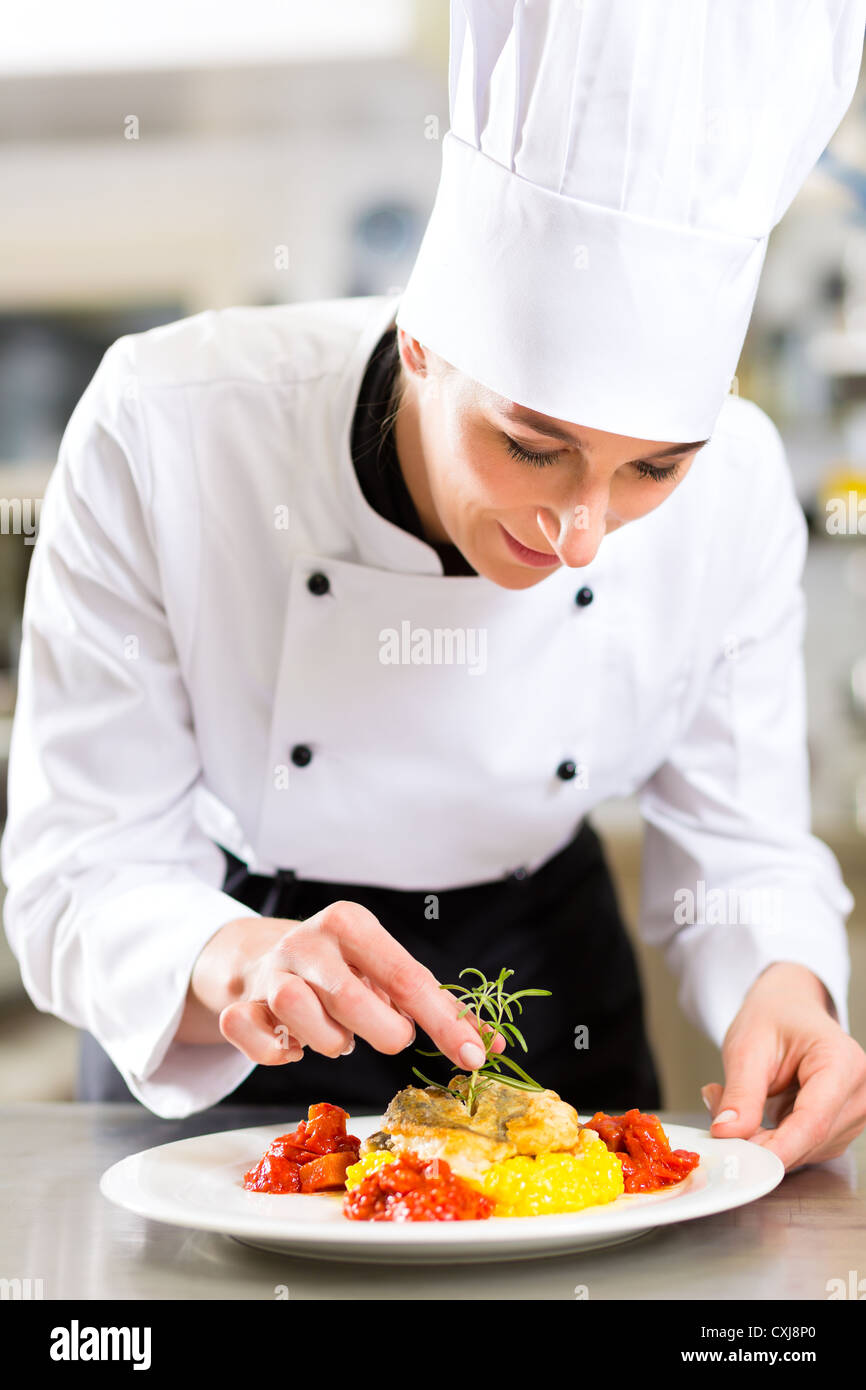 Lo Chef femmina in hotel o al ristorante Cucina Cucina, lei sta finendo un piatto sulla piastra Foto Stock