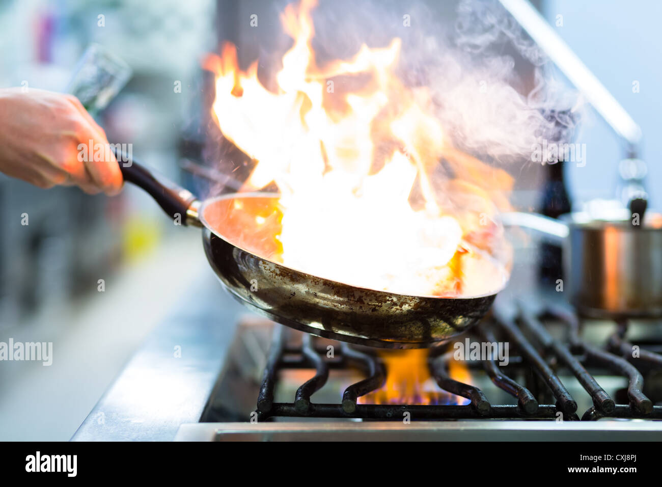 Lo chef del ristorante la cucina in stufa con pan, facendo flambe sui prodotti alimentari Foto Stock