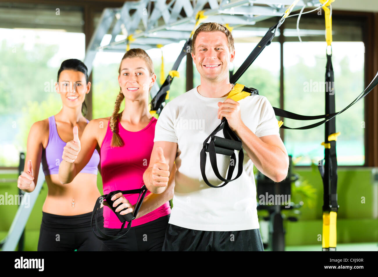Gruppe von Menschen trainieren mit Schlingentrainer oder trainer di sospensione in Fitnessstudio Foto Stock