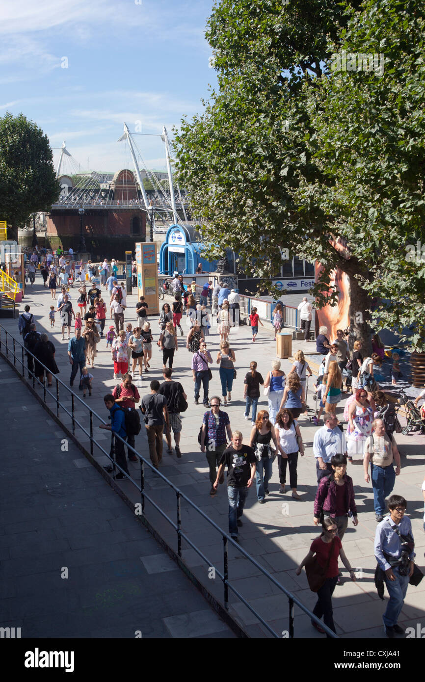 Folla estiva a piedi lungo il fiume presso il South Bank Foto Stock