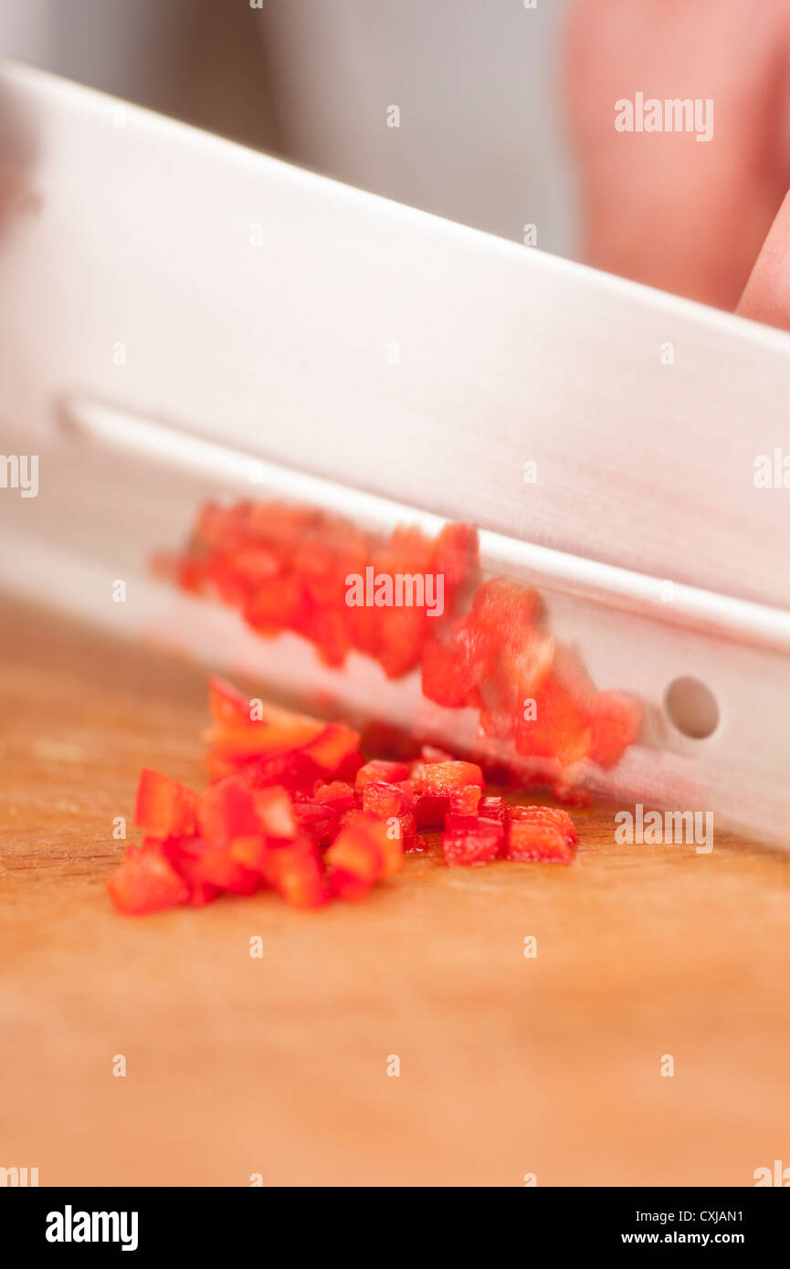 Vista dettagliata del peperoncino rosso tritato essendo da uno chef su un tagliere di legno Foto Stock