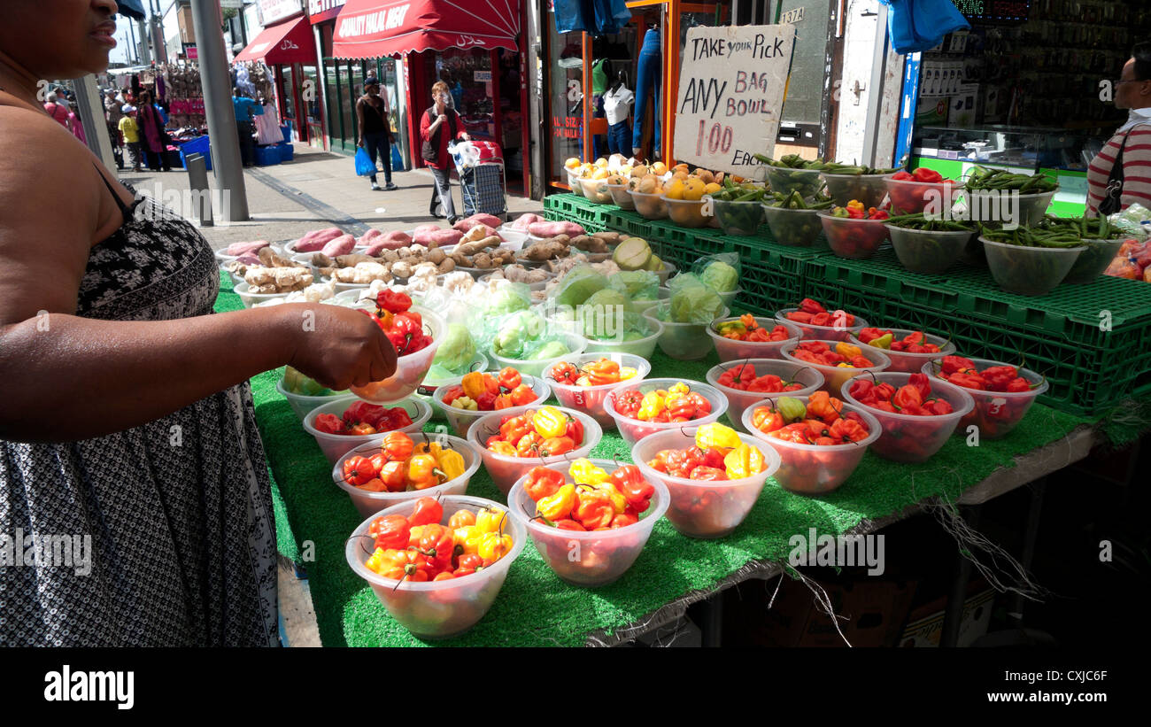 Donna che acquista peperoni rossi caldi Scotch Bonnet Peperoncini chilis Market stalla a Walthamstow High Street, East London Inghilterra Regno Unito KATHY DEWITT Foto Stock