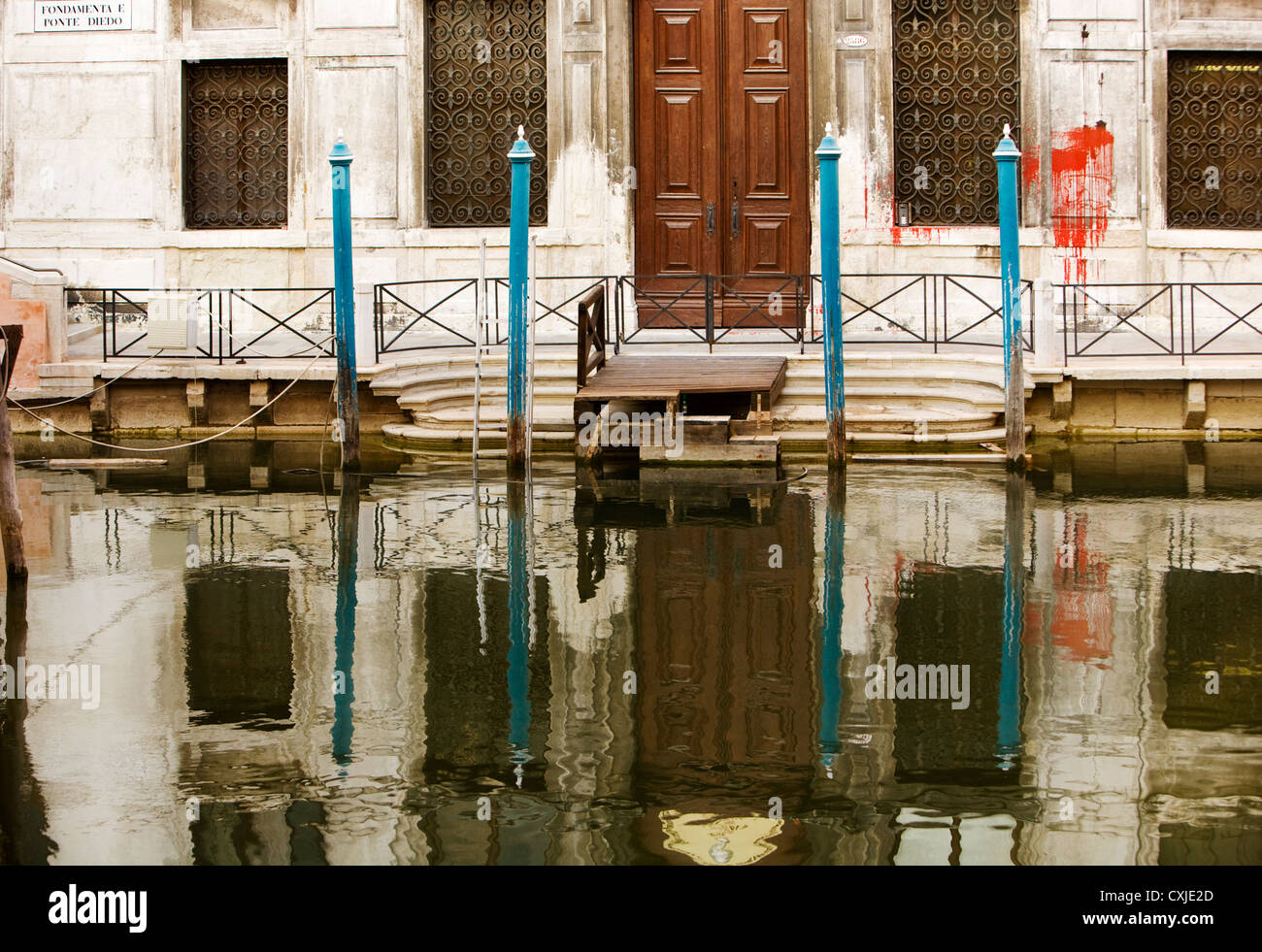 Una spruzzata rossa di vernice su una casa con copertura si riflette in un canale, Venezia Foto Stock